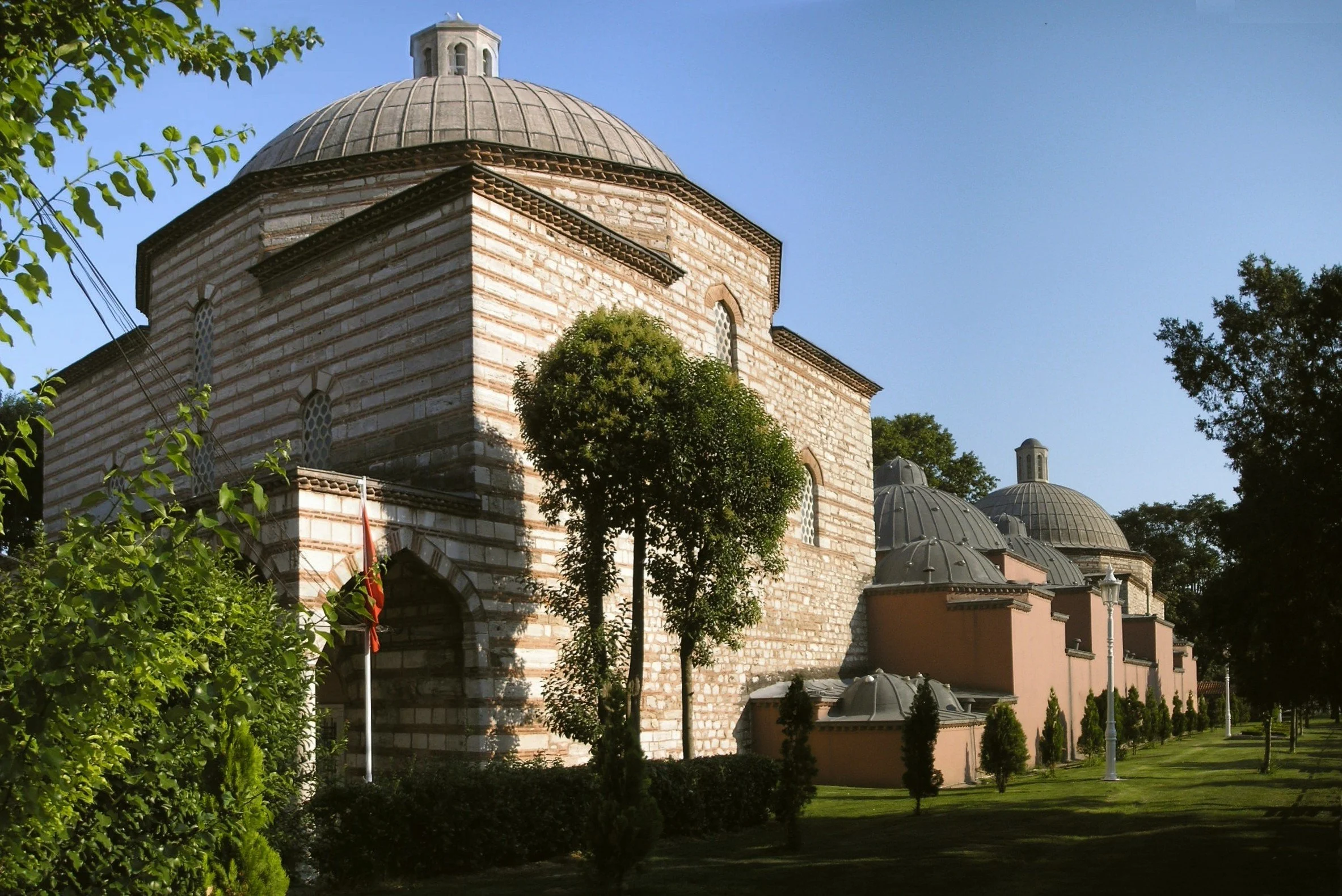 Hürrem Sultan Hamam, a domed stone building with striped masonry and a large tree in front, Istanbul.