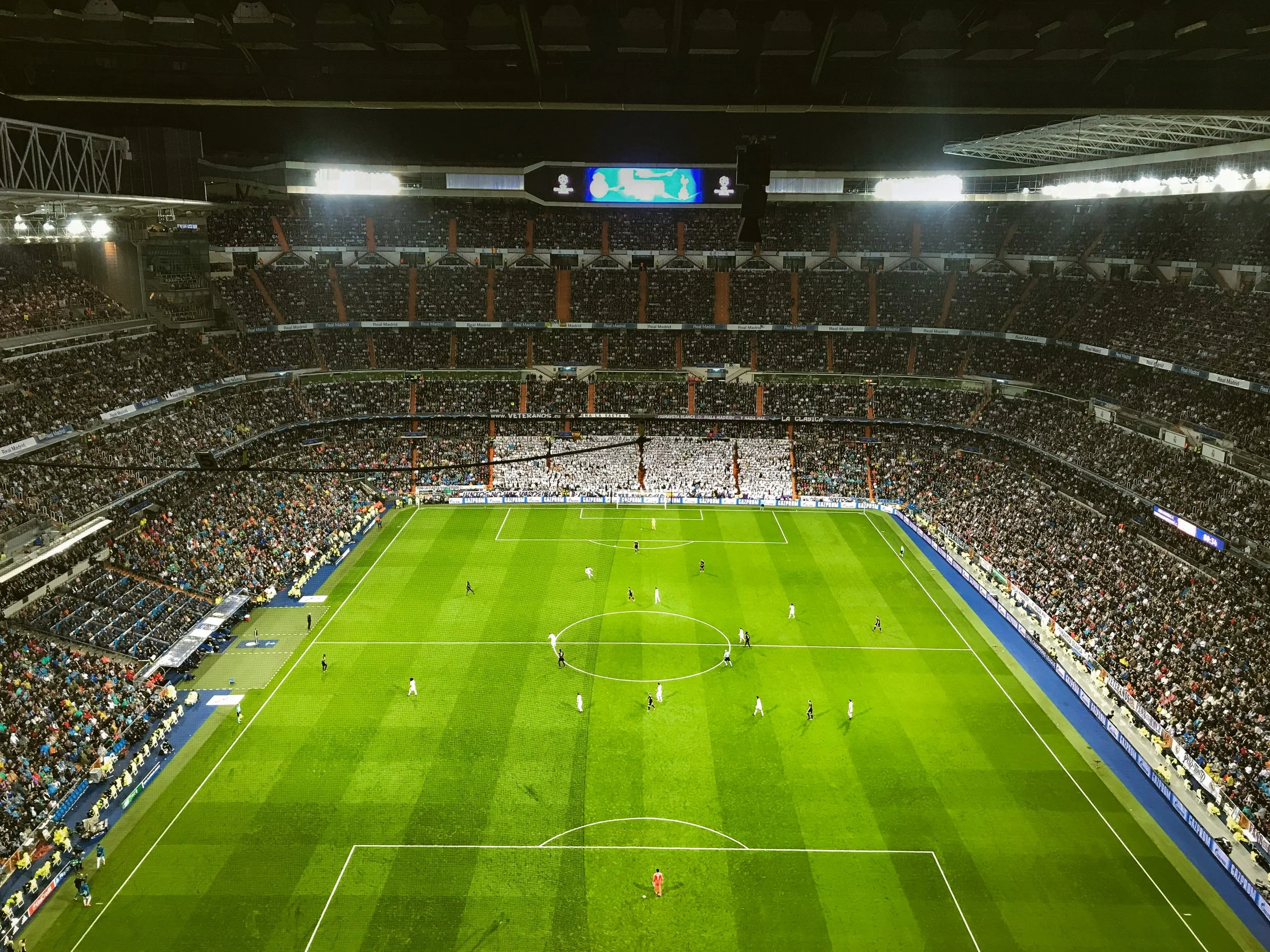 Real Madrid's Santiago Bernabéu football stadium with a bright green pitch and packed stands seen from above, Madrid