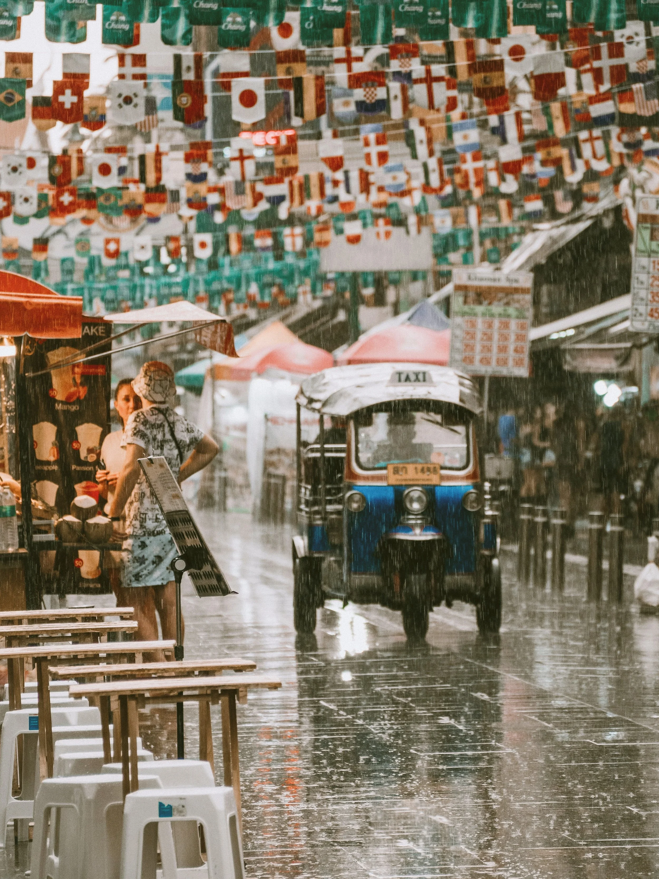 Tuk-tuk on a rain-soaked street under hanging red decorations, Bangkok.