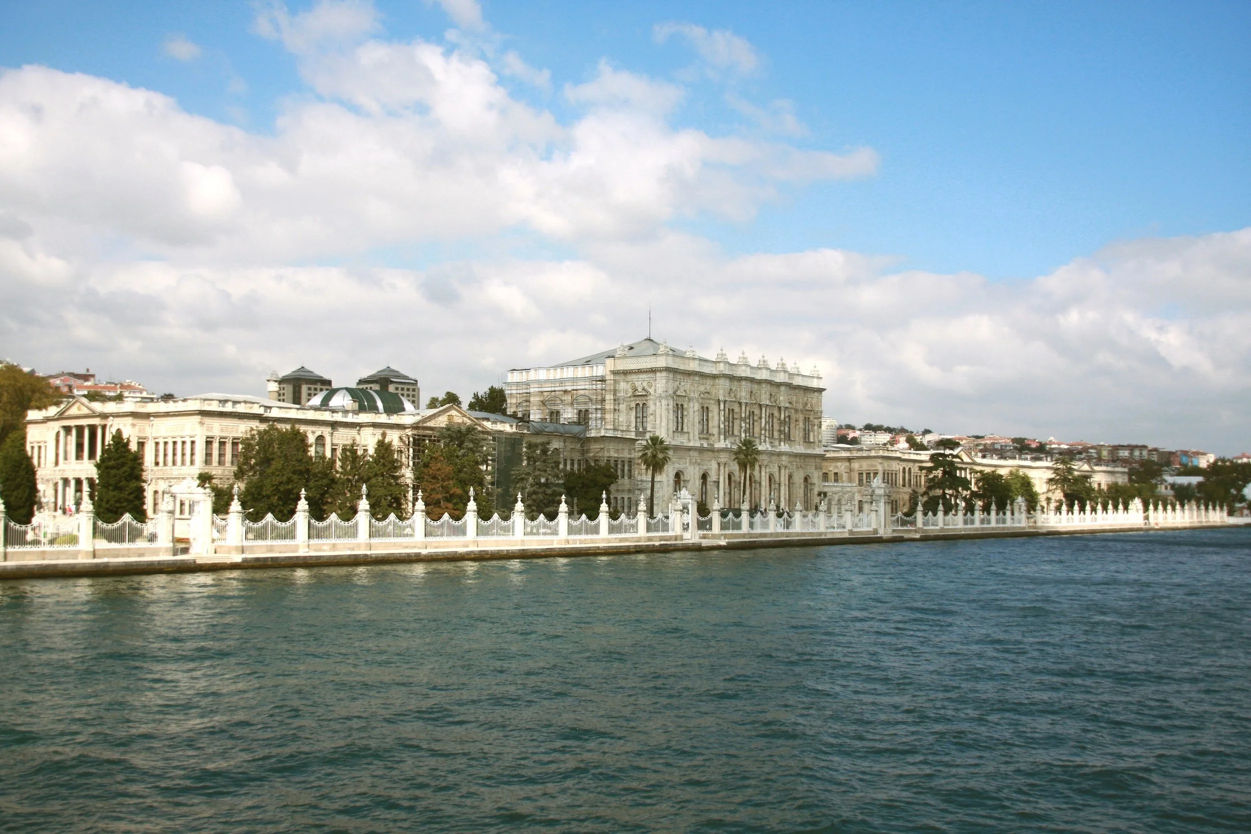 Dolmabahçe Palace on the shore of the Bosphorus under a blue sky with scattered clouds, Istanbul.
