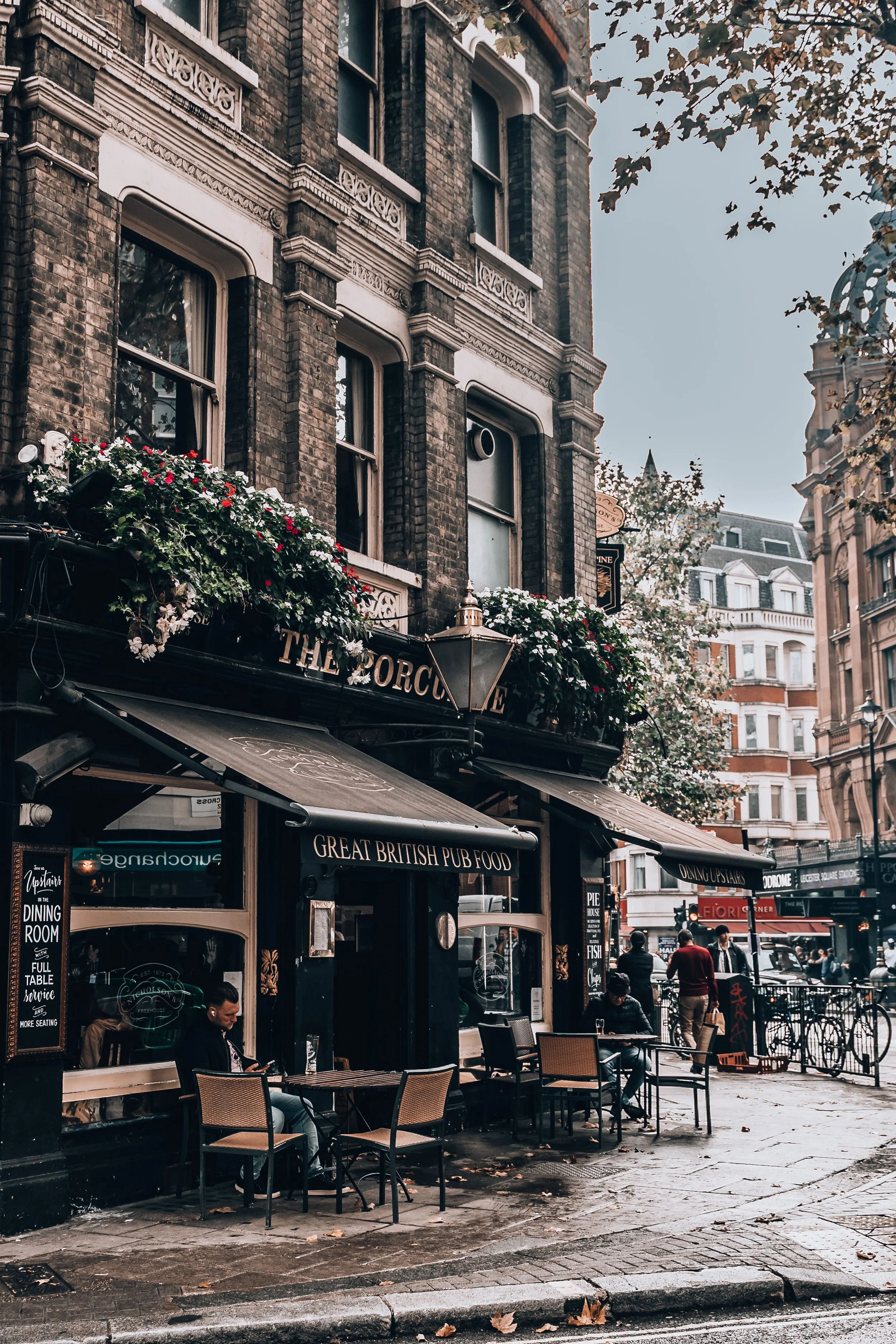 Narrow street lined with shopfronts and pub signs, London.