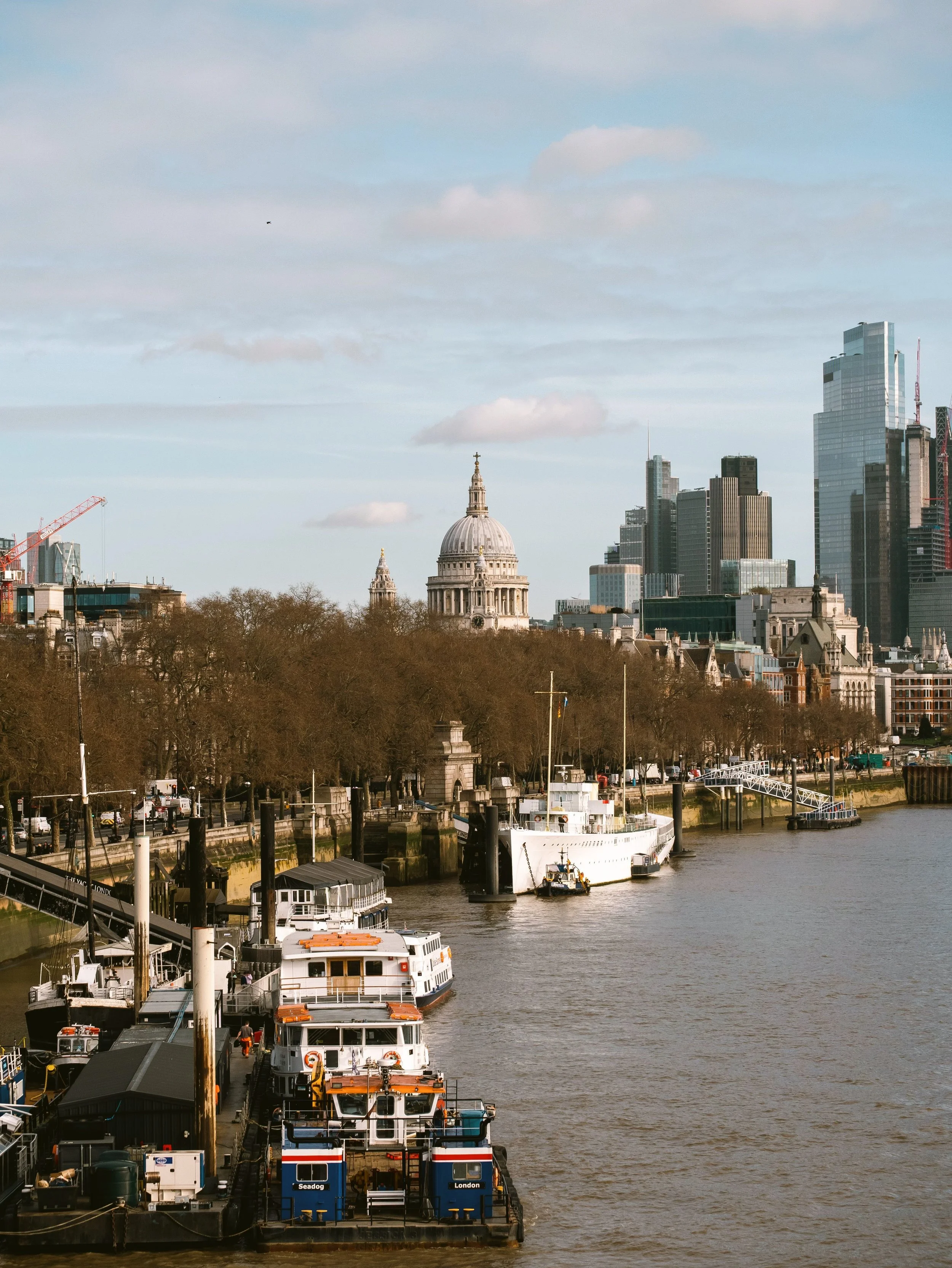 Boats moored on the River Thames with the City of London skyline behind