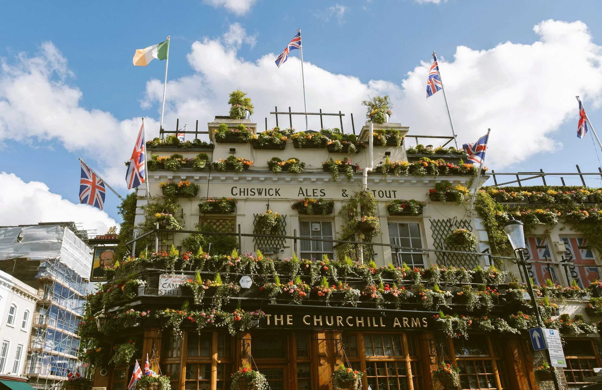 Churchill Arms pub with its facade covered in flowers and Union Jack flags, London