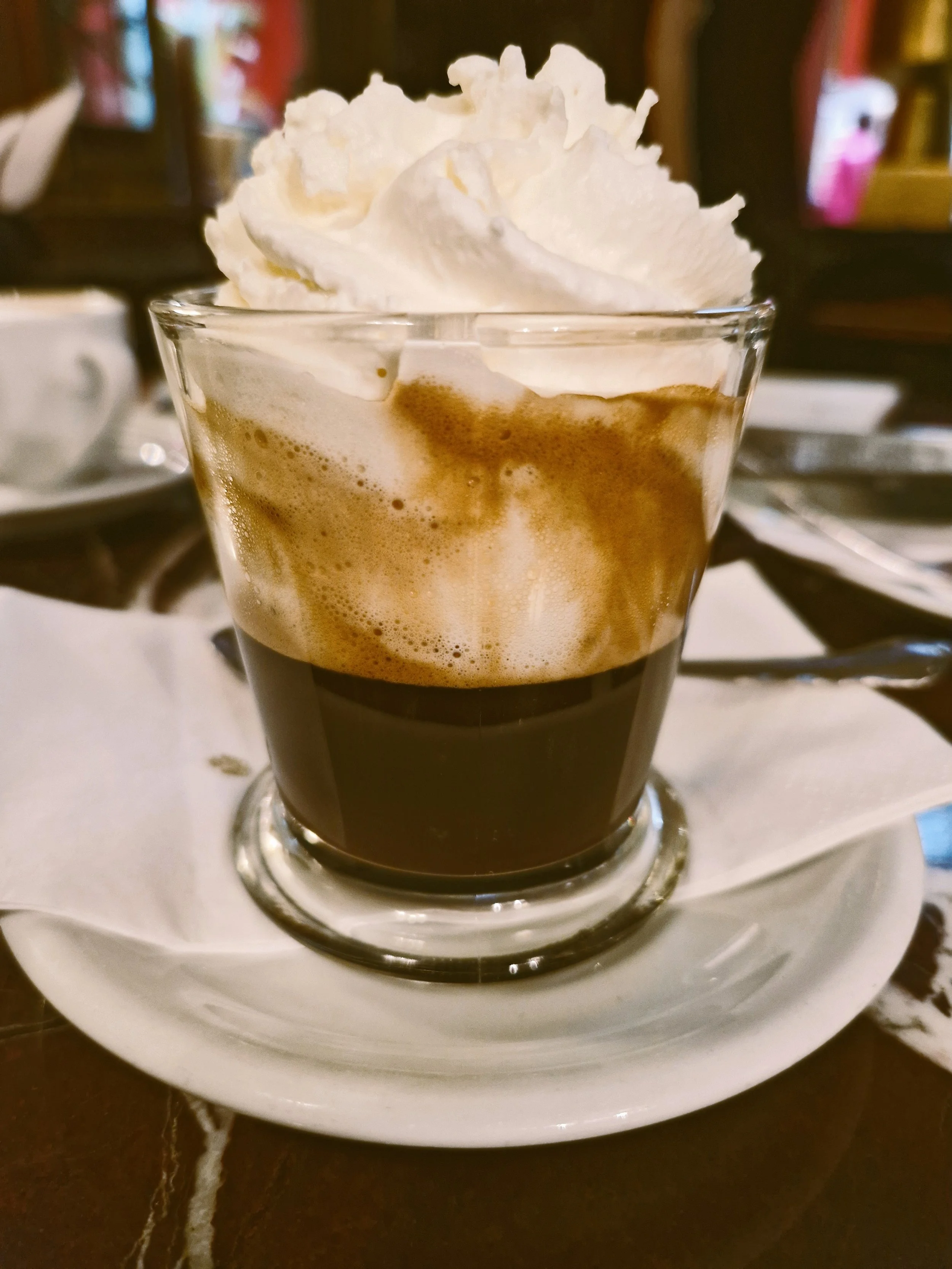 Einspänner coffee topped with whipped cream in a glass on a saucer, Vienna.