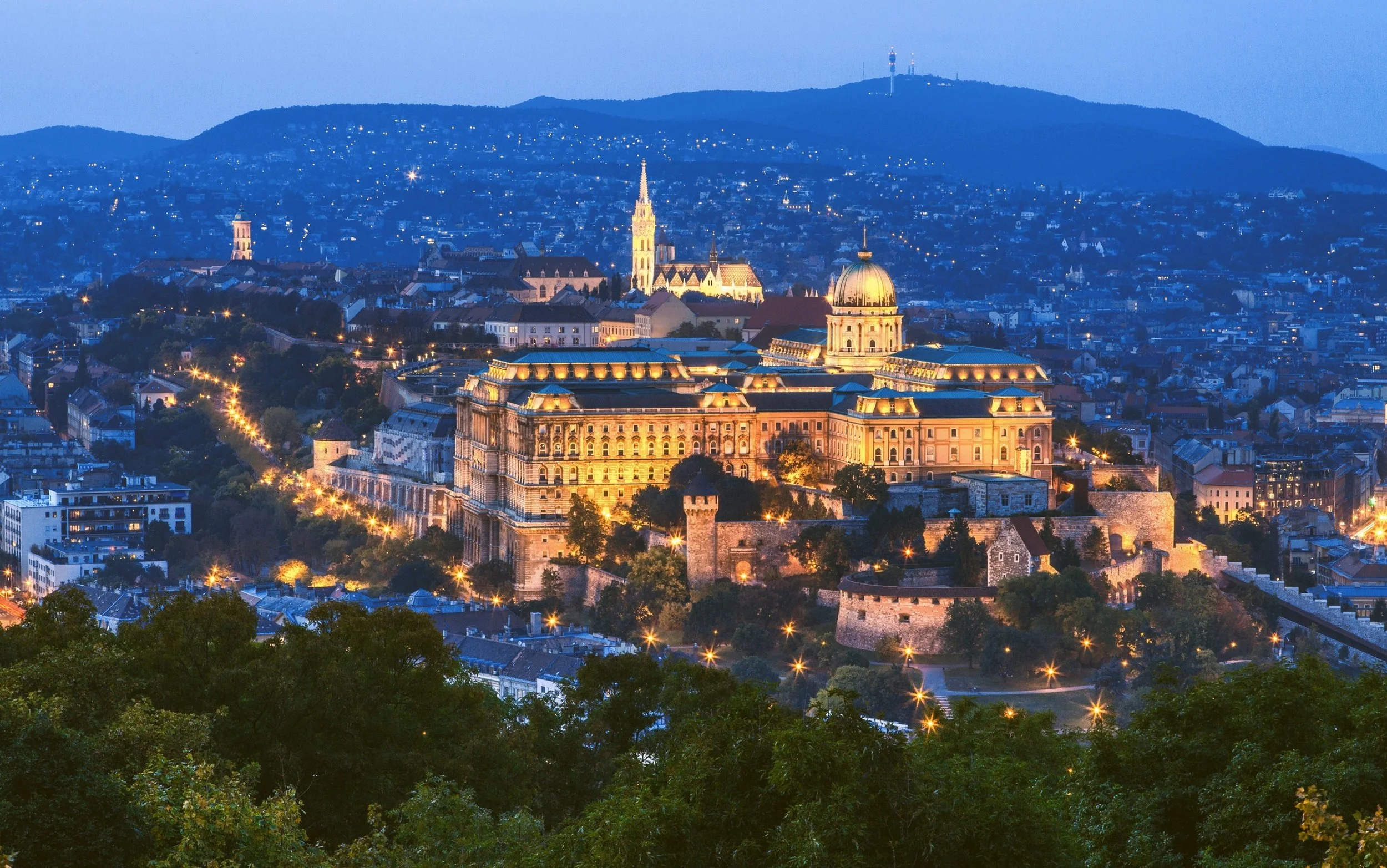 Buda Castle illuminated at dusk on its hill above Budapest