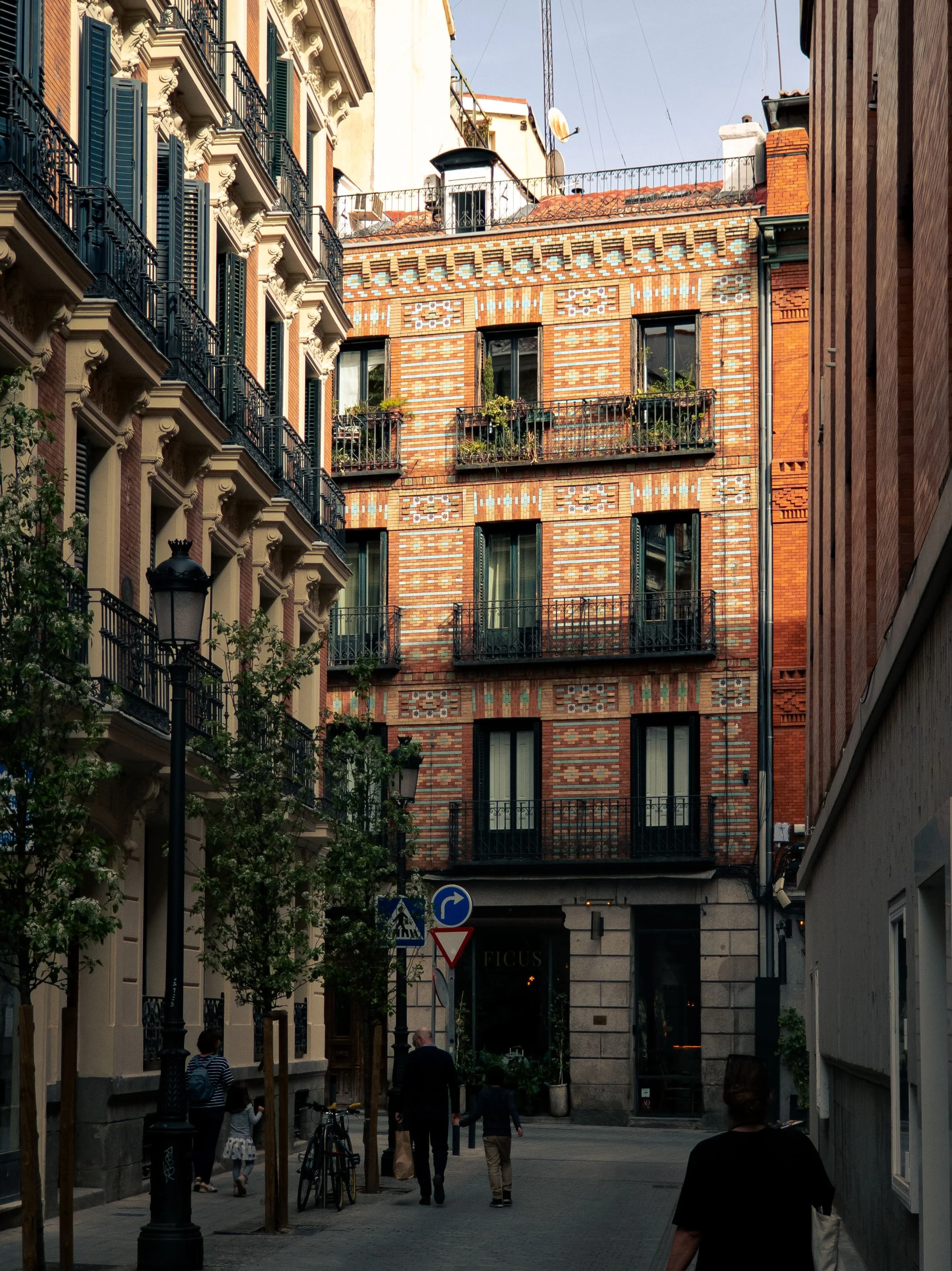 Patterned brick building with wrought-iron balconies on a narrow street in Barrio de las Letras, Madrid