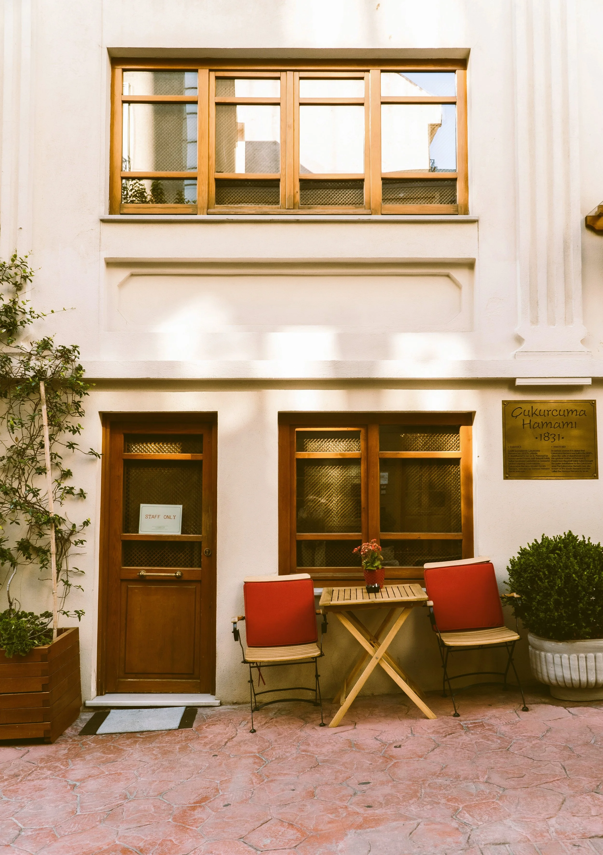 Small cream-colored building with a wooden door and a table outside, Istanbul.