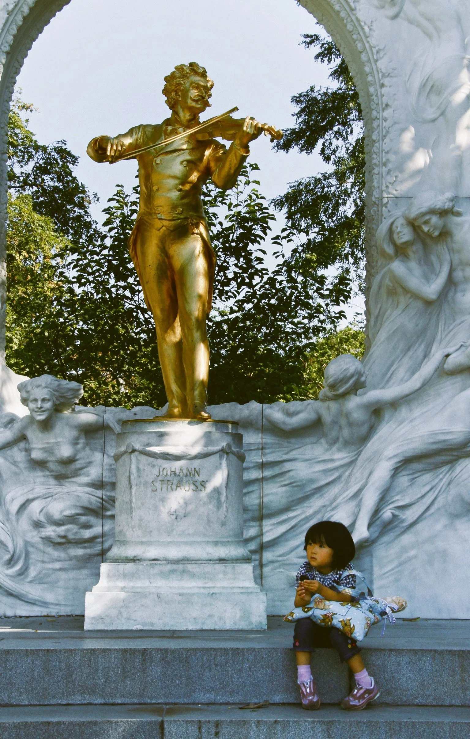 A young girl sitting on a step in front of the Johann Strauss statue, Vienna.