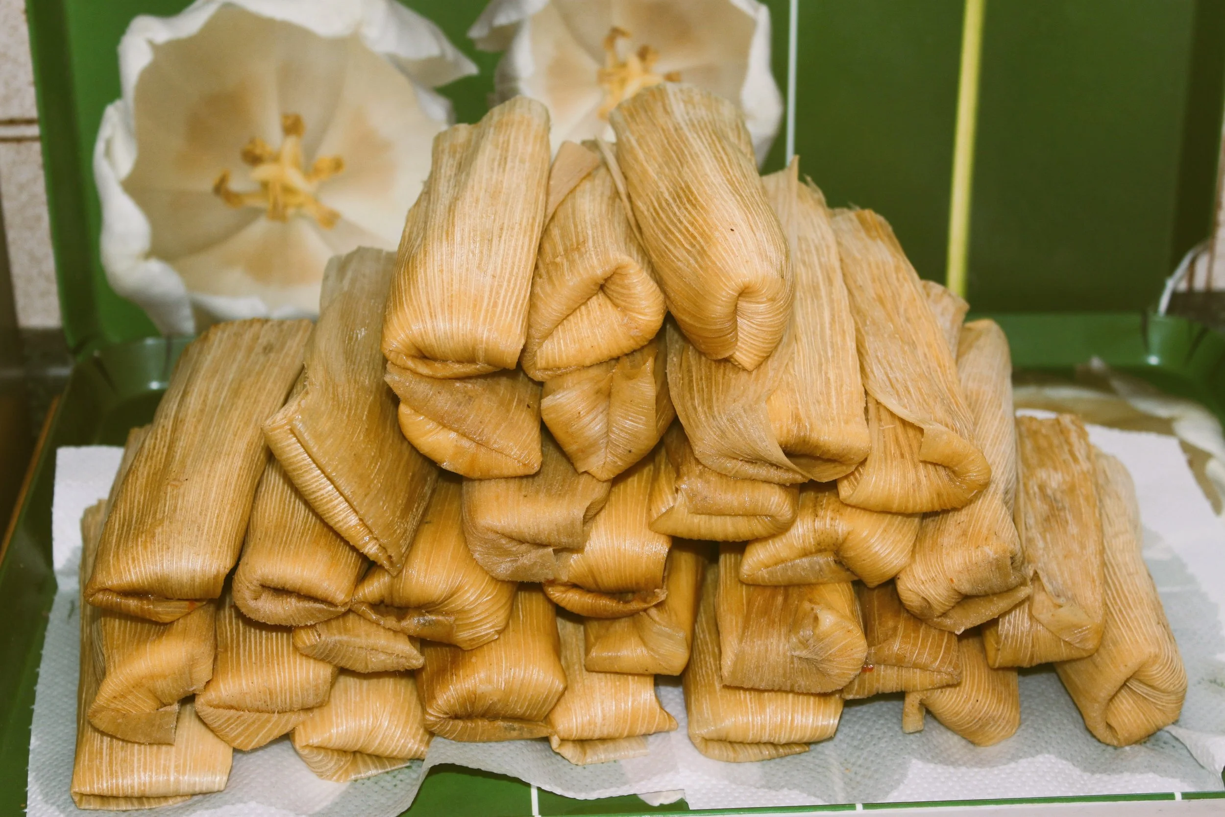 Stack of tamales on a plate with corn husks in the background, Mexico City.