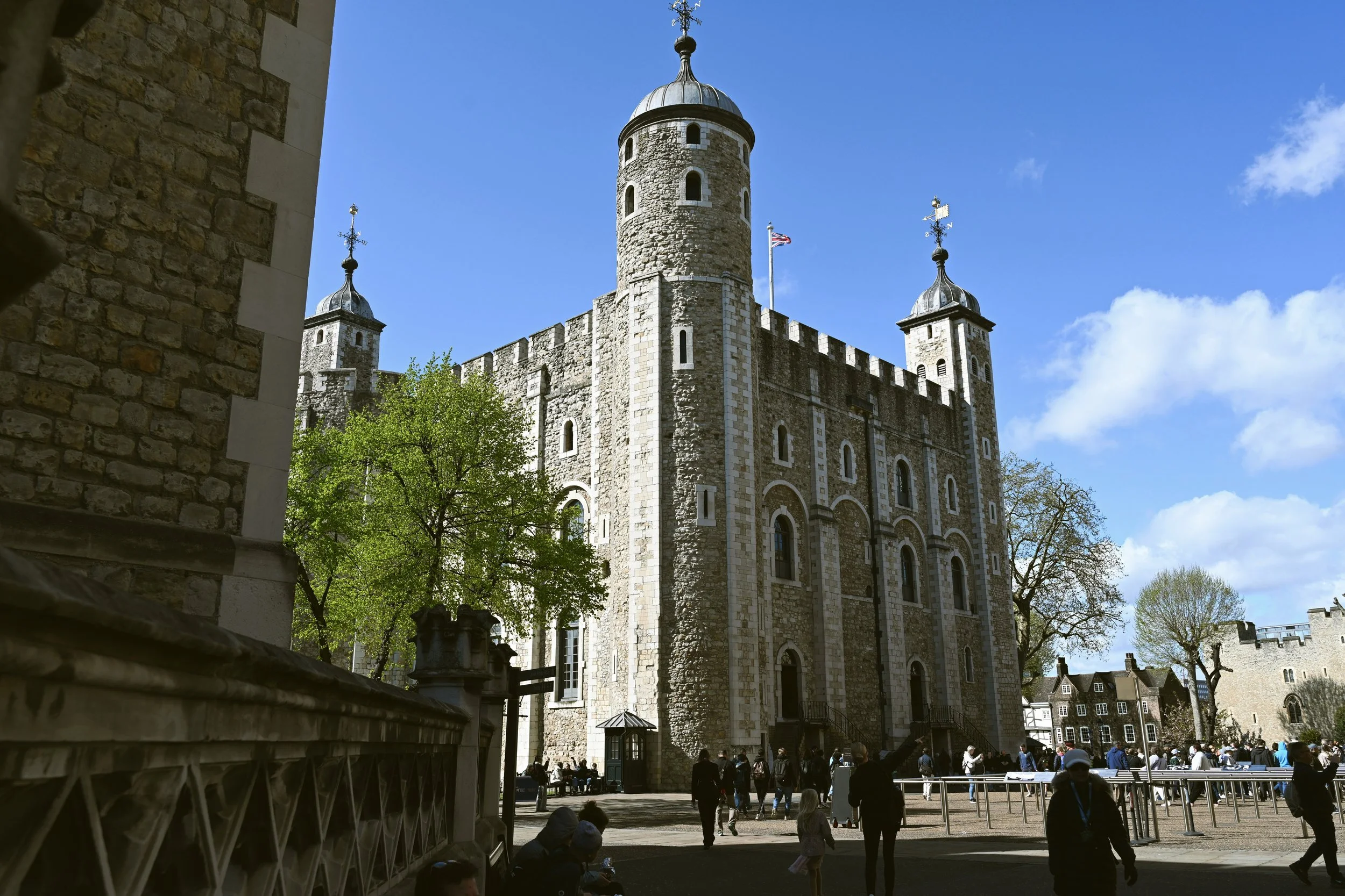 The White Tower rising above the grounds of the Tower of London under a blue sky