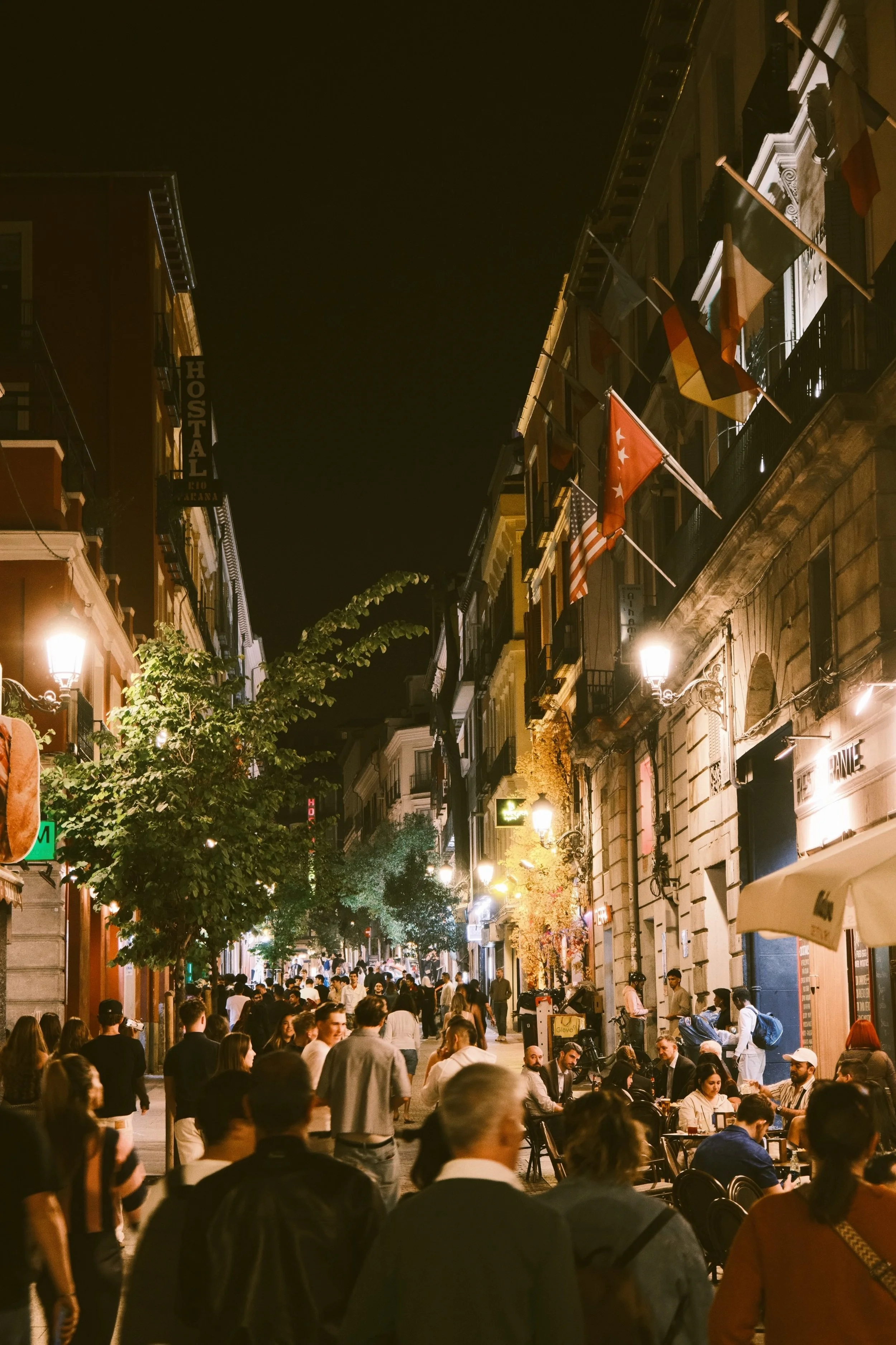 Crowded street at night with people gathered beneath balconies and hanging lights, Madrid
