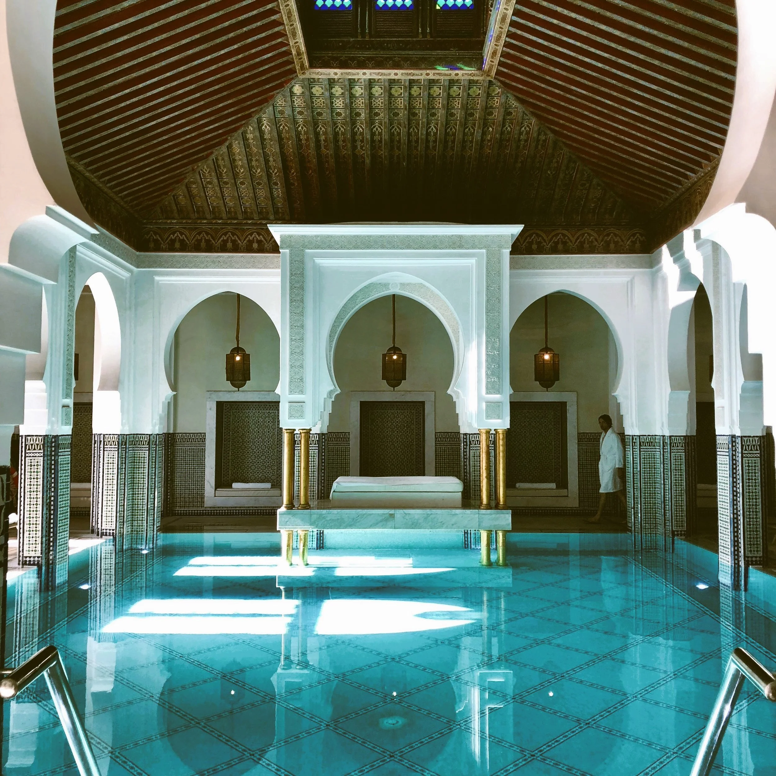 La Mamounia indoor pool with white Moorish arches, hanging lanterns and zellige tilework, Marrakech.