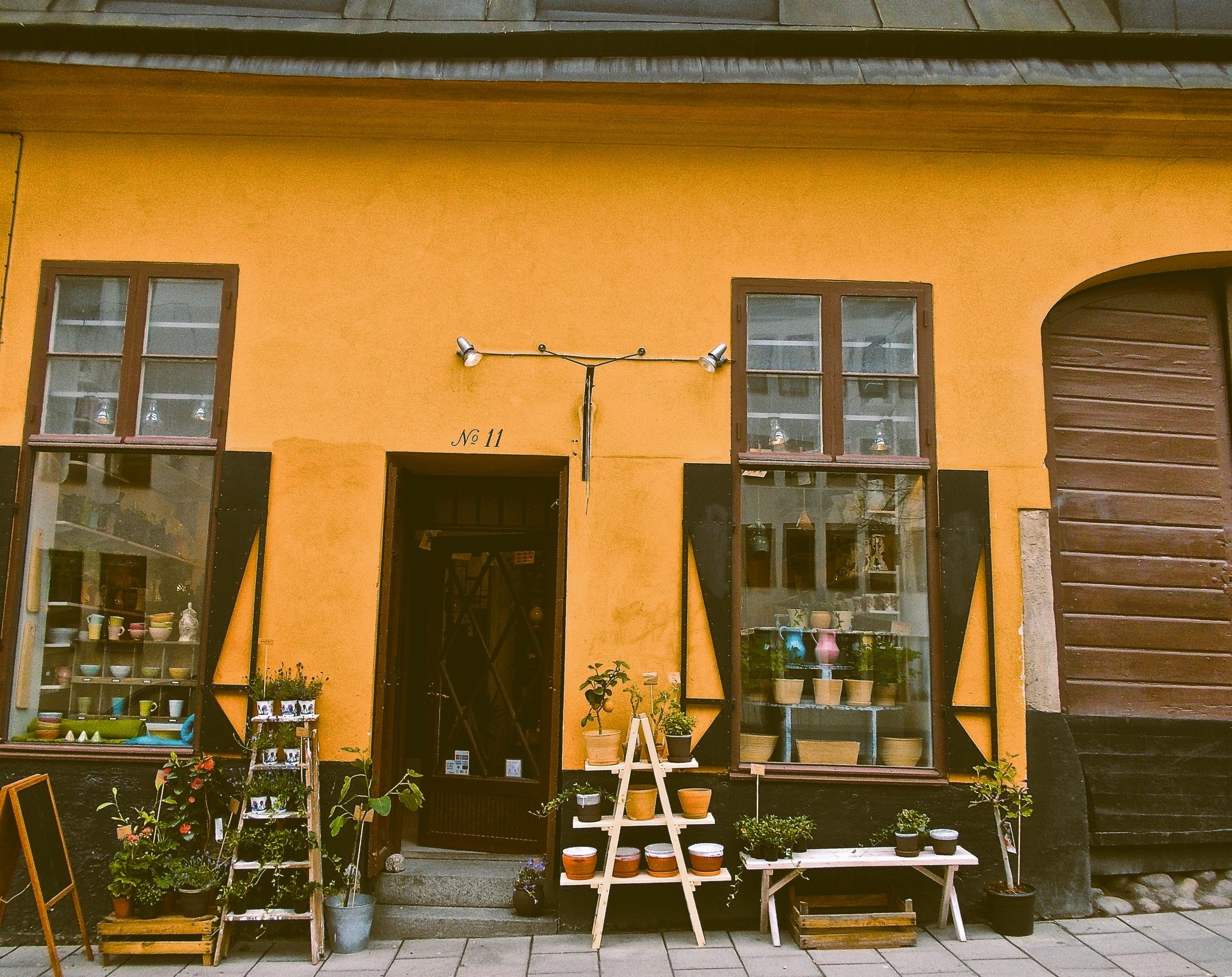 Small ochre-fronted shop with vintage goods displayed on the street in Södermalm, Stockholm