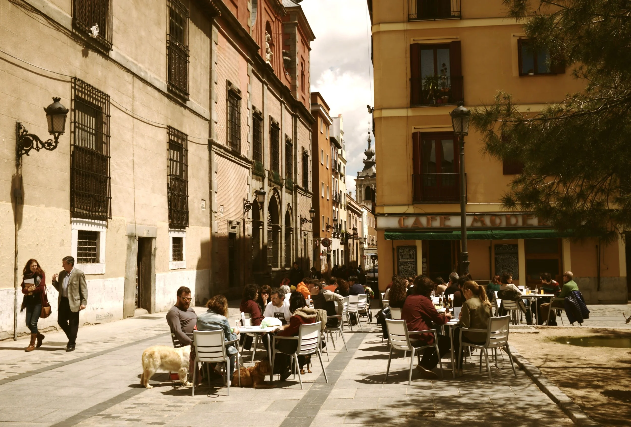 Terraces filling a quiet corner between warm-toned buildings in Malasaña, Madrid