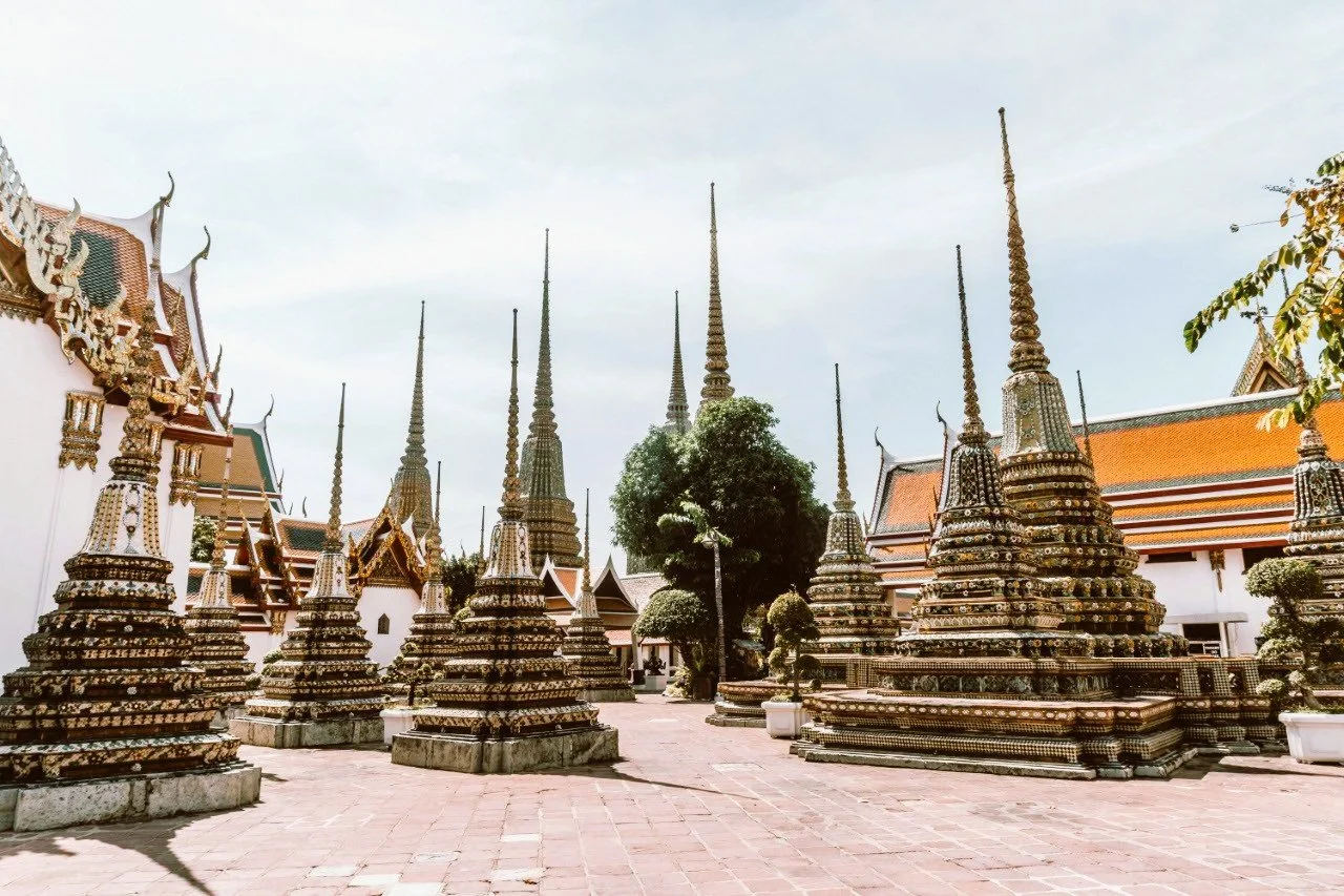 Rows of small tiered chedis in a temple courtyard under a pale sky, Wat Pho, Bangkok.
