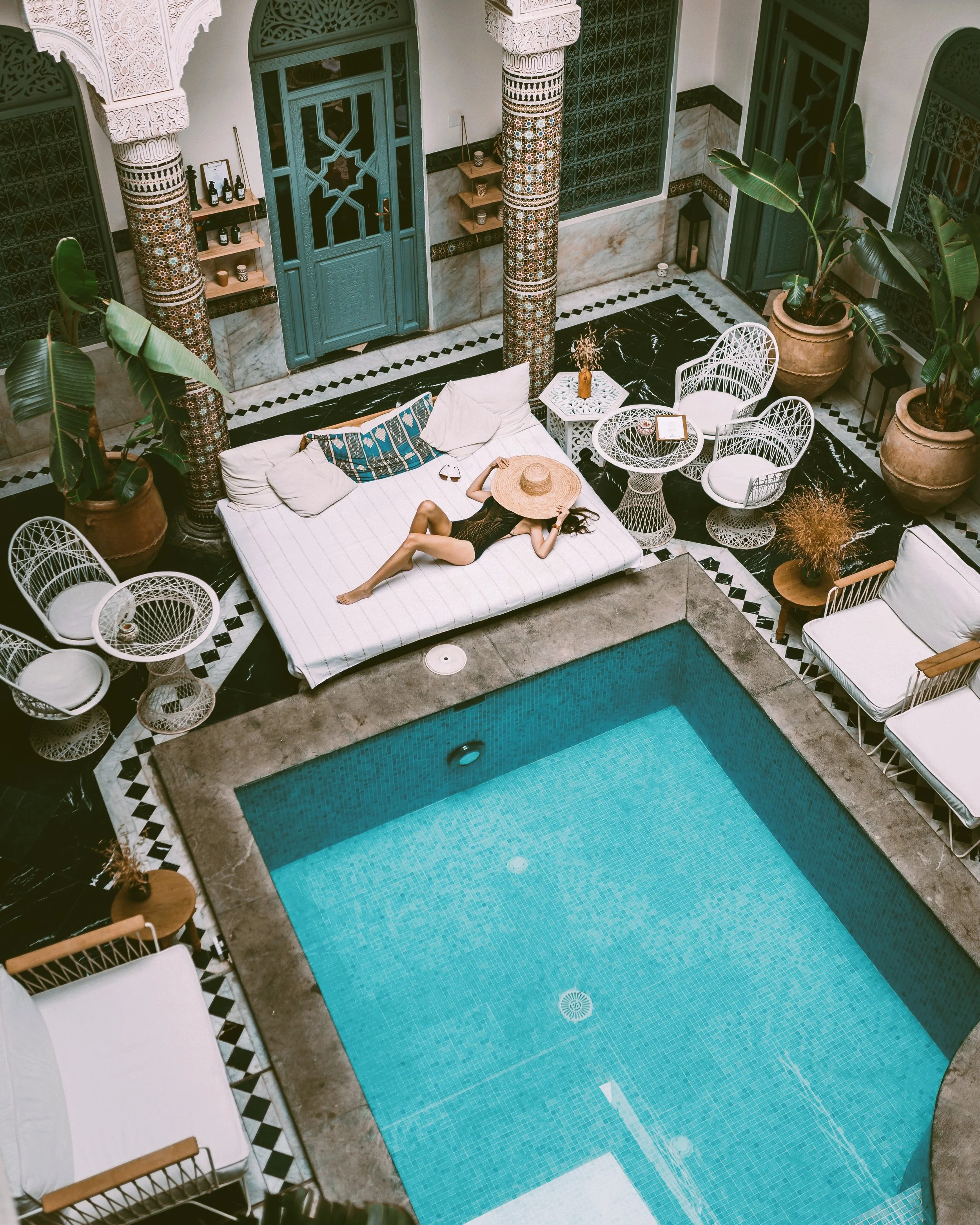 Riad courtyard seen from above with a turquoise pool surrounded by loungers and plants, Marrakech.