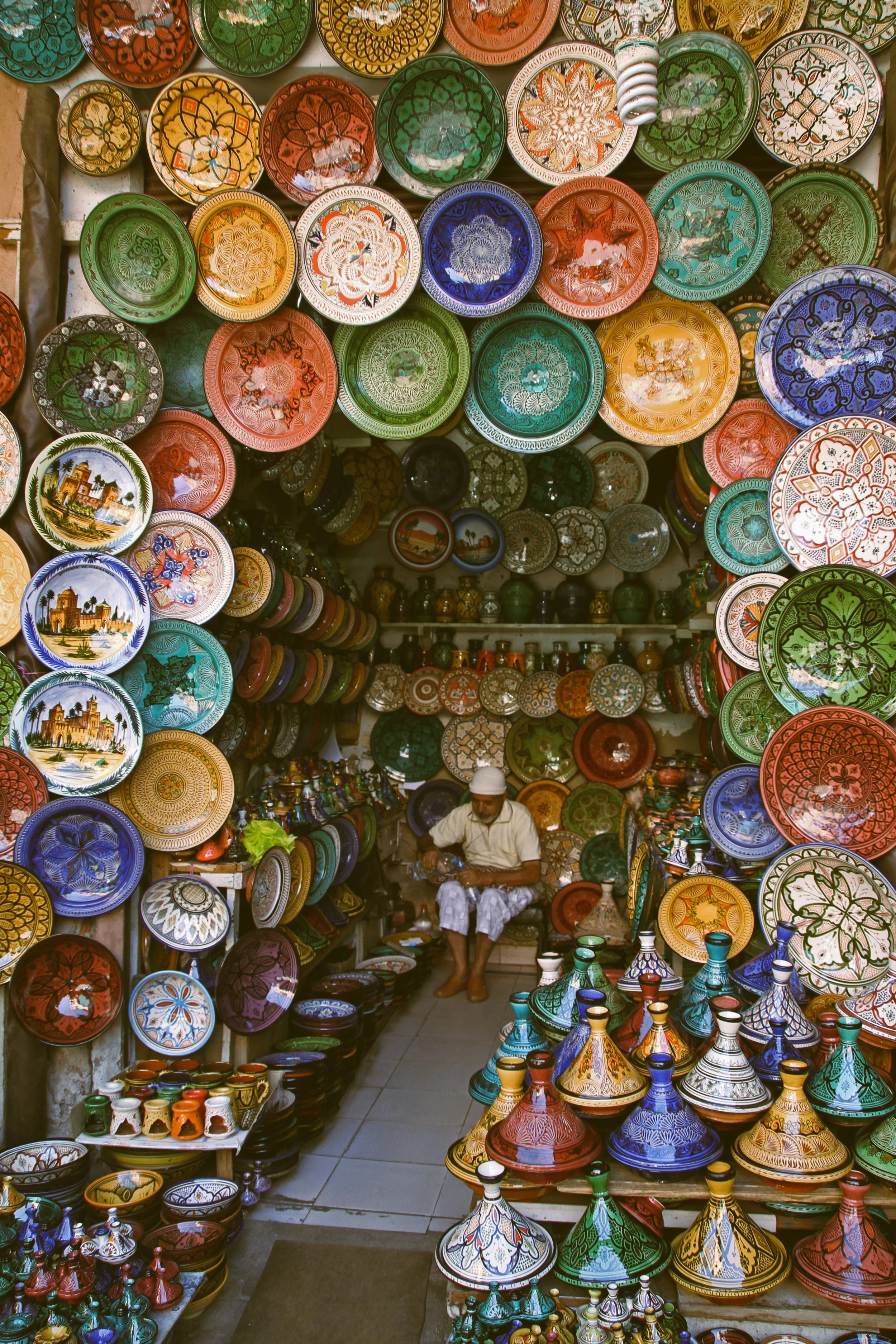 Souk entrance framed by colorful hand-painted ceramic plates and lamps, Marrakech.