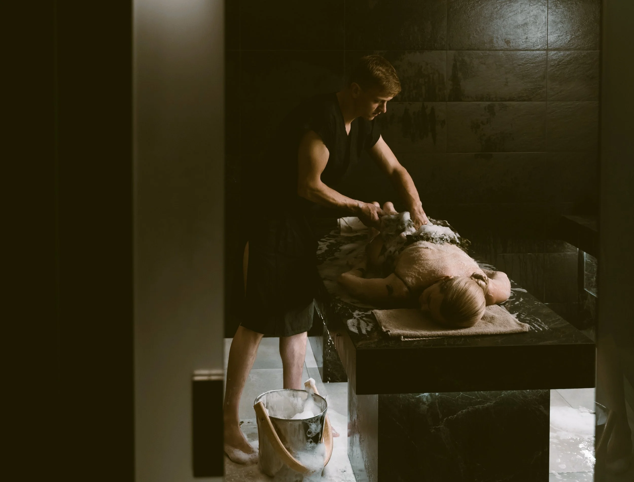 Person receiving a massage on a marble slab in a dimly lit hamam, Istanbul.