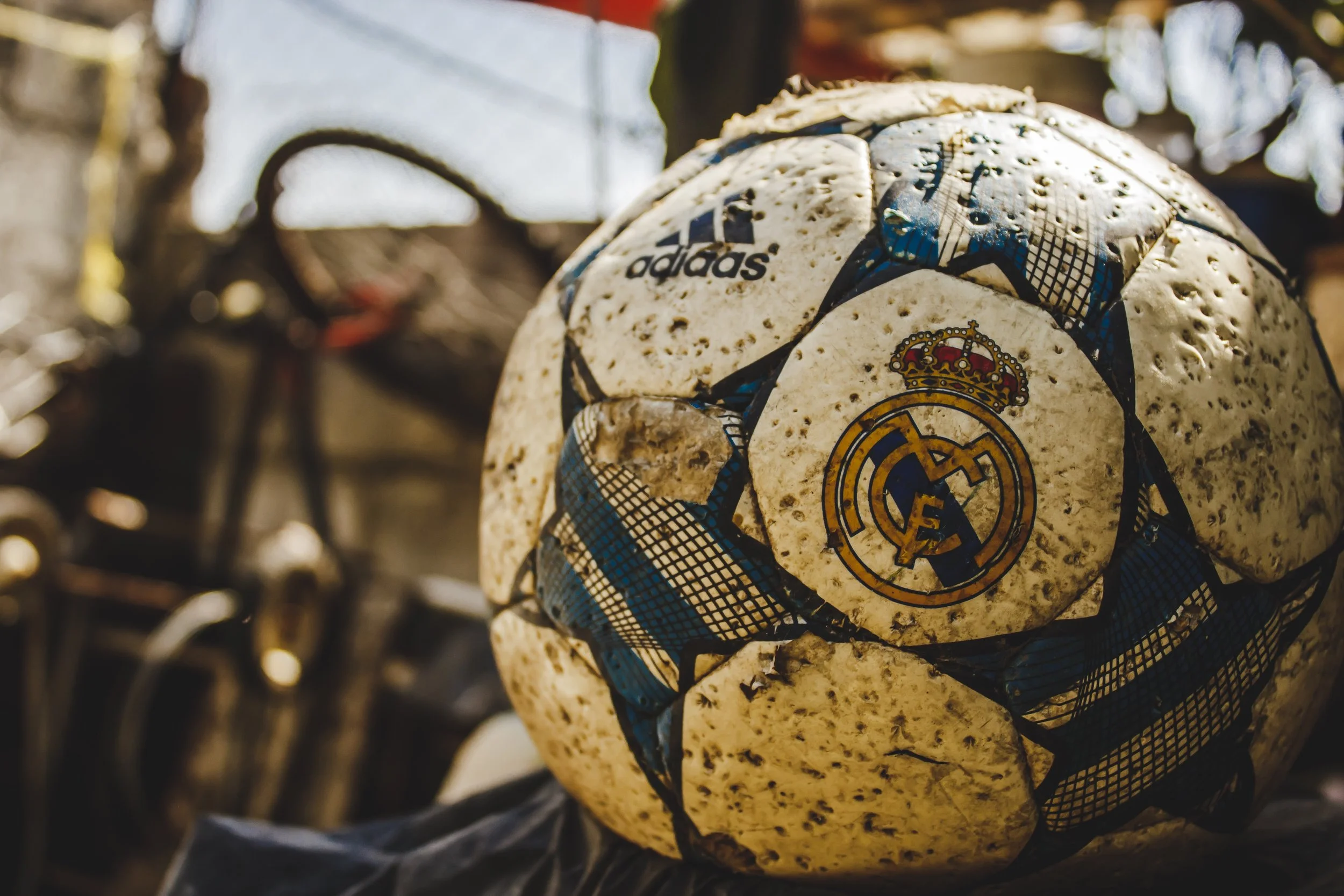 Worn football with a Real Madrid crest resting among bicycles in a street shop