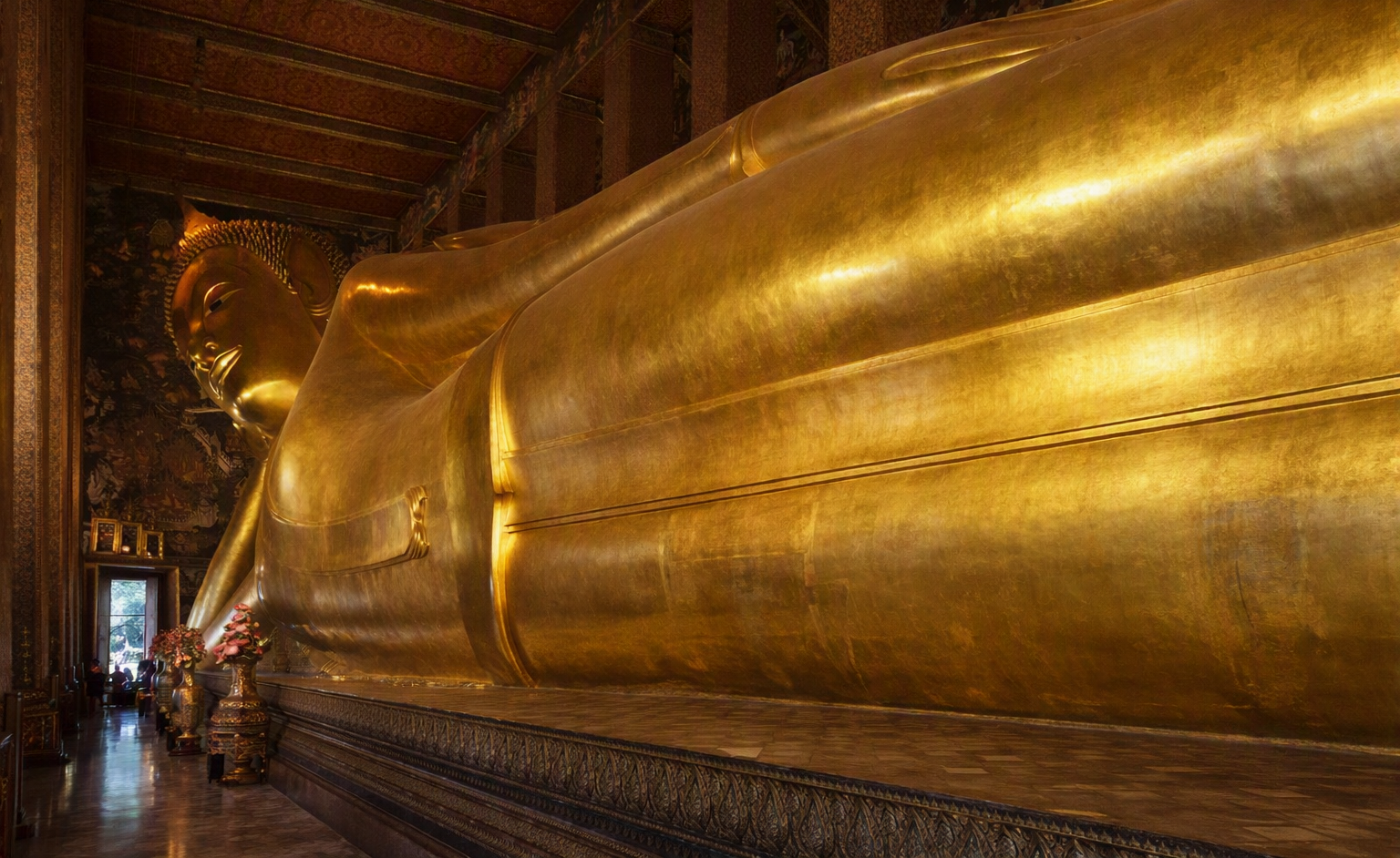 Giant golden Reclining Buddha statue filling a temple hall, Wat Pho, Bangkok.