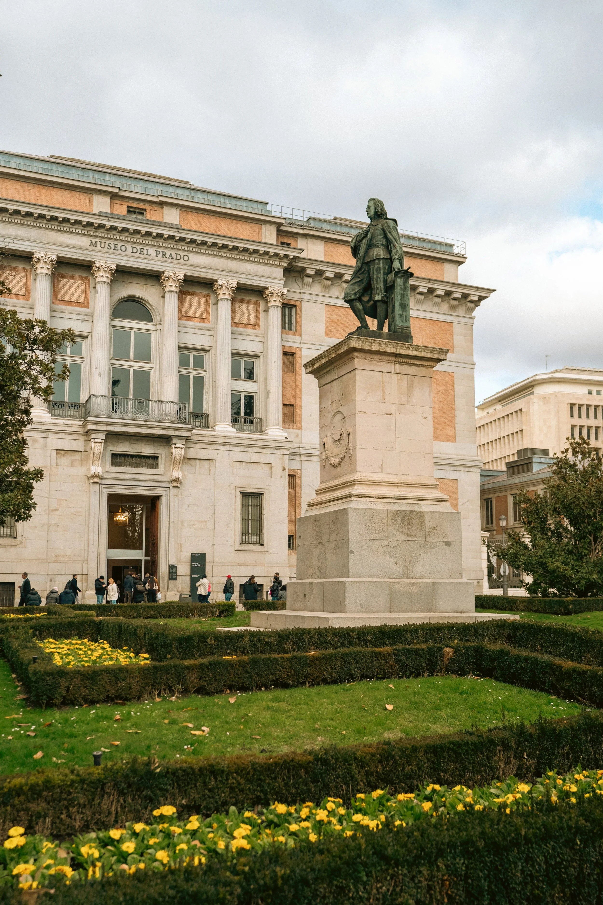 Statue of Diego de Velázquez in front of Museo del Prado with yellow flowers, Madrid