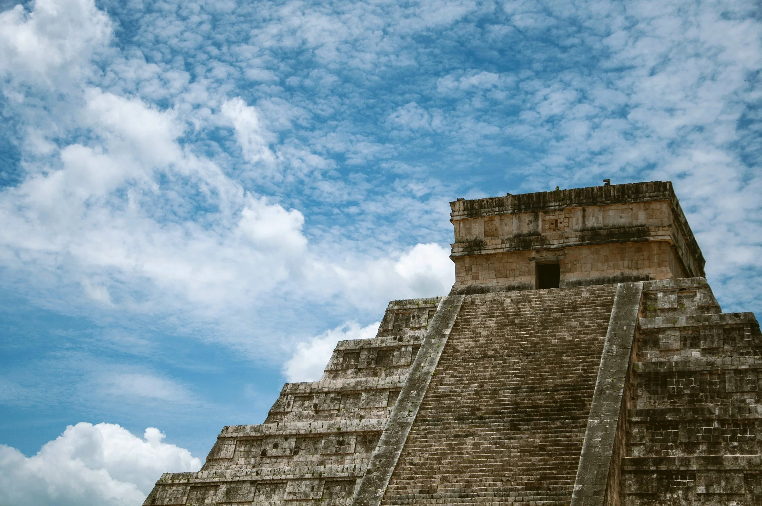 Stepped stone pyramid under a blue sky with white clouds, Teotihuacán, Mexico.