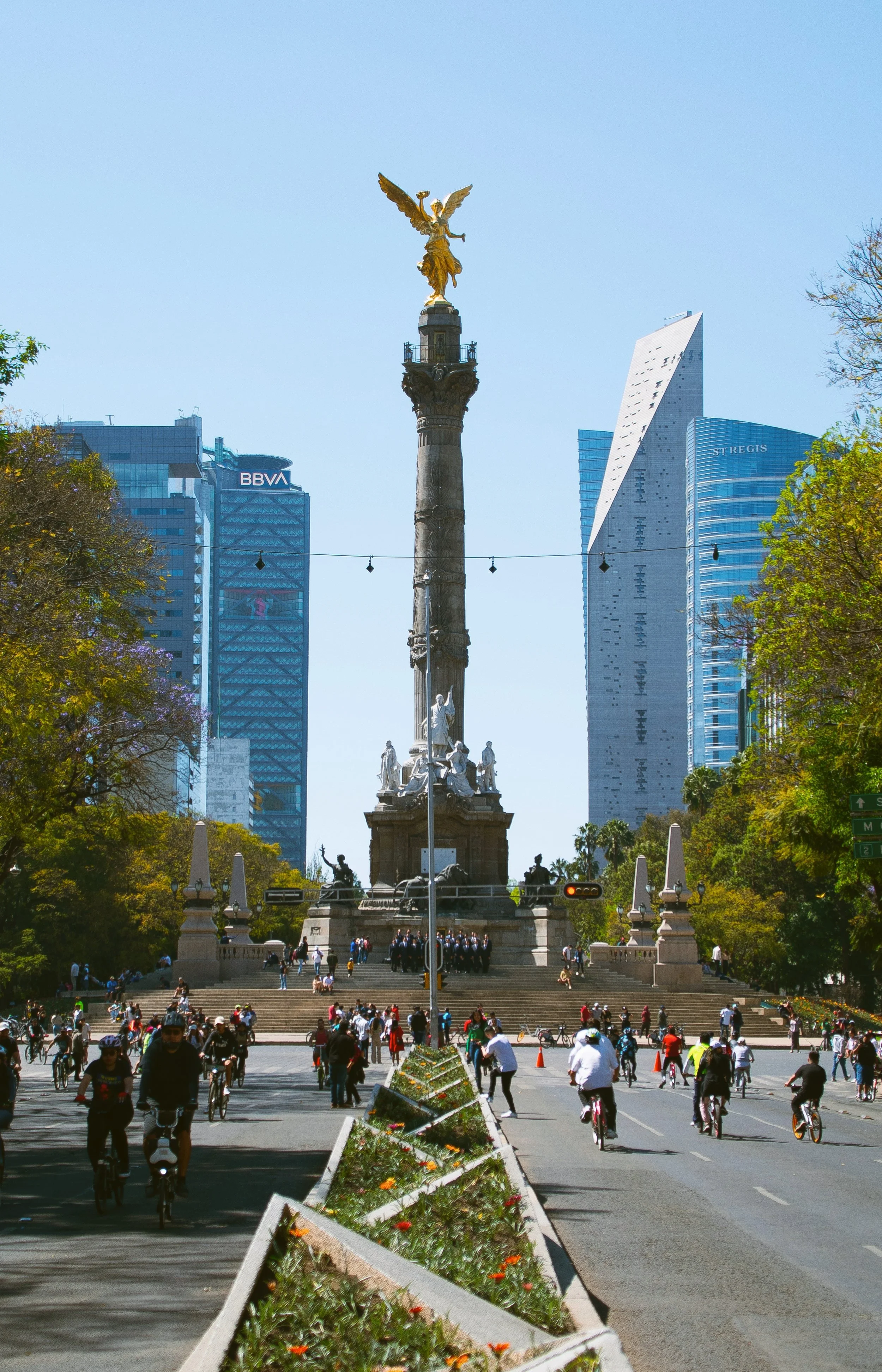 Angel of Independence column topped with a golden winged statue on Paseo de la Reforma, with modern towers behind, Mexico City.