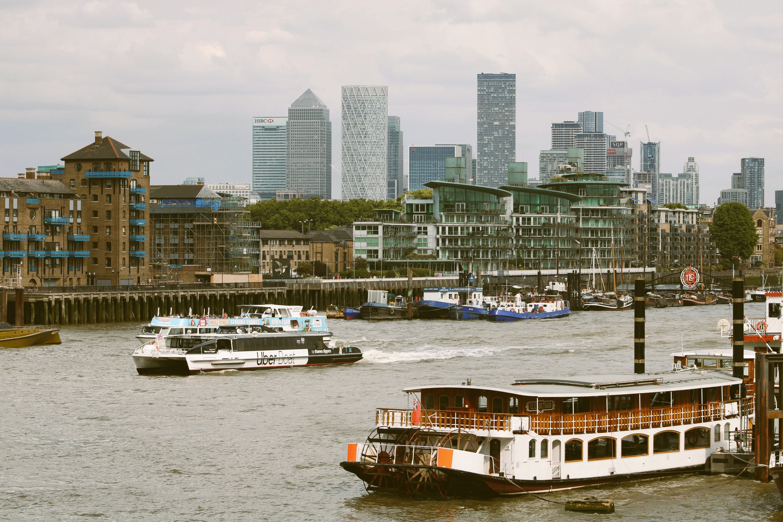 Boats on the River Thames with Tower Bridge and the Canary Wharf skyline behind, London