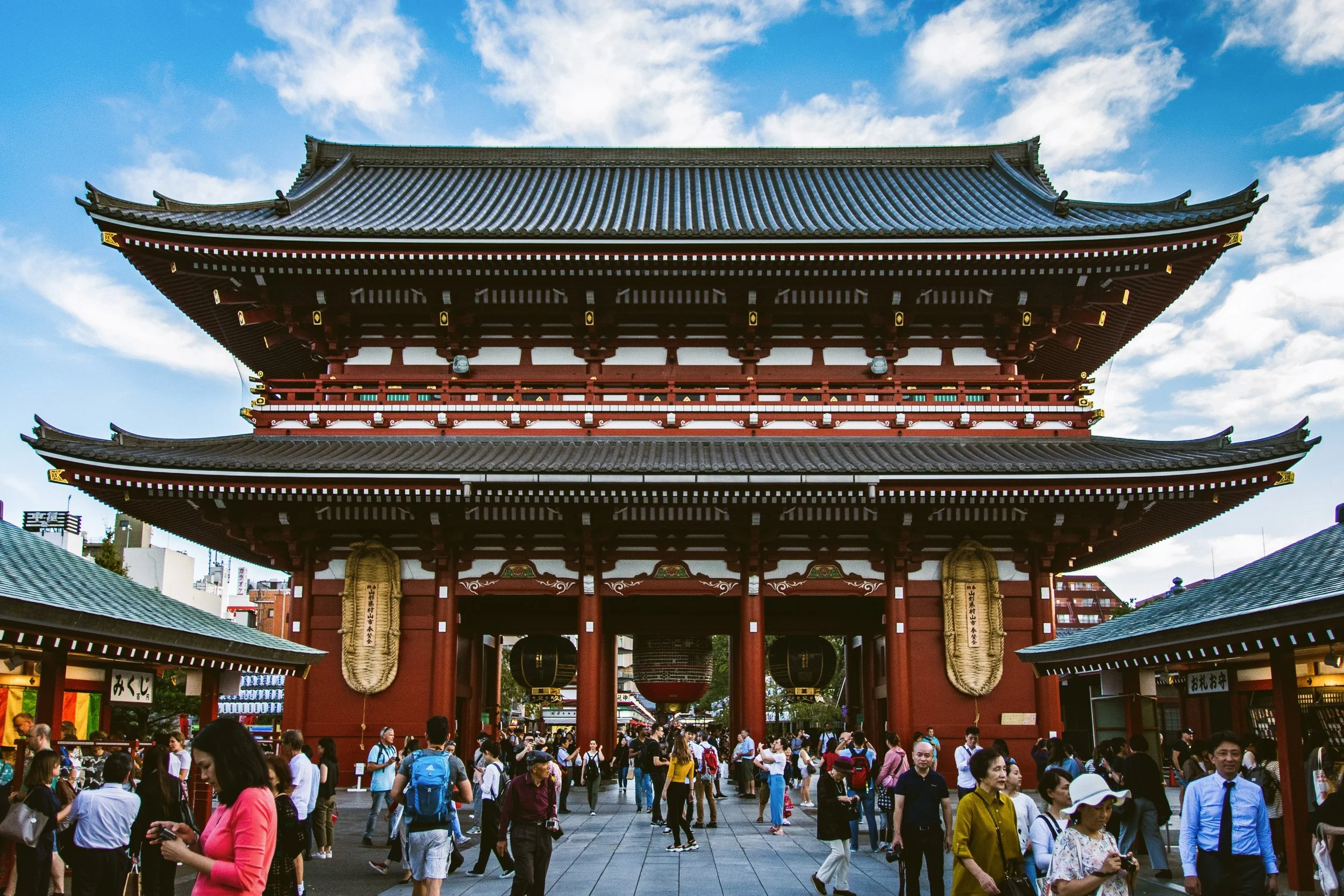 Hōzōmon Gate with its red columns and tiled roof, with crowds of visitors in front under a blue sky, Sensō-ji, Asakusa, Tokyo