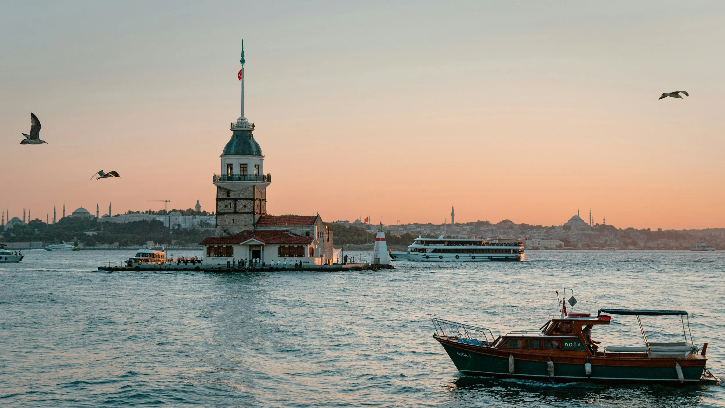 Maiden's Tower (Kiz Kulesi) on a small islet in the Bosphorus at sunset, with a boat passing in the foreground, Istanbul.