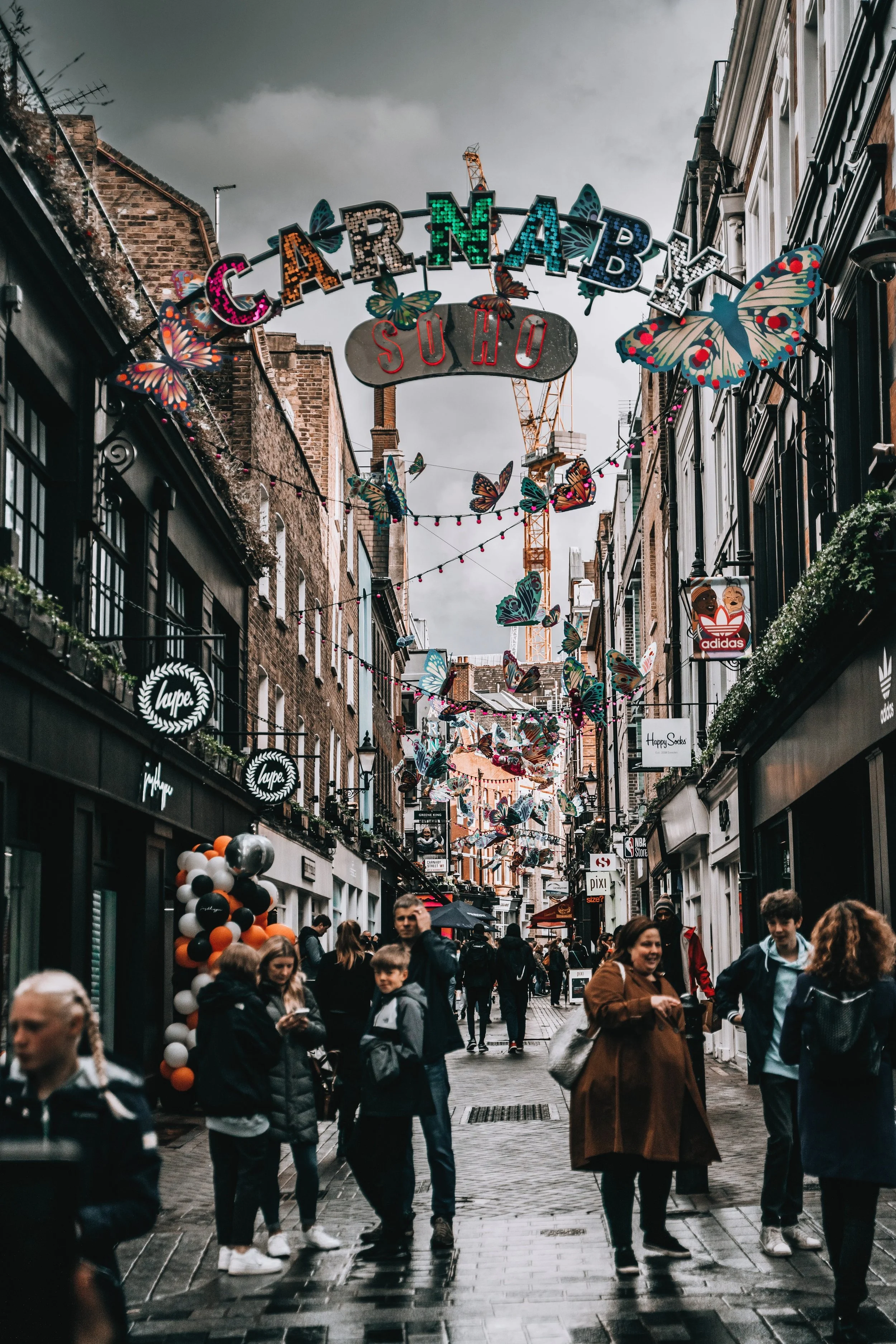 Crowded pedestrian street decorated with red lanterns on Carnaby Street in Soho, London