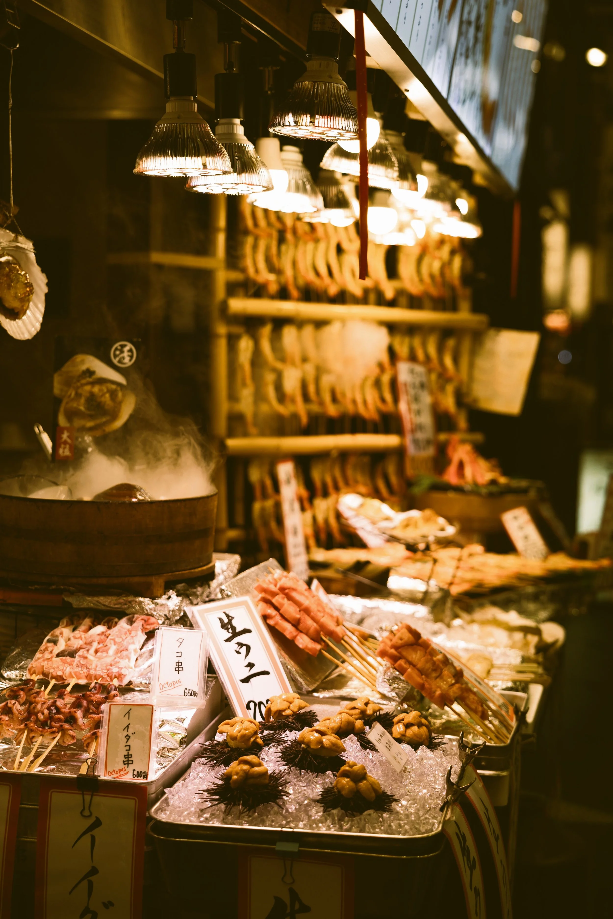 Fish market stall with fresh seafood on display under warm lighting, Tokyo.