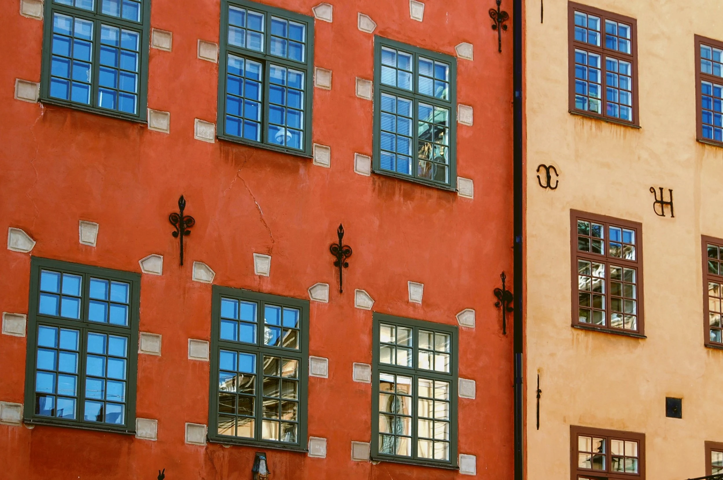 Blue-framed windows on a red townhouse facade beside an ochre one, Gamla Stan, Stockholm