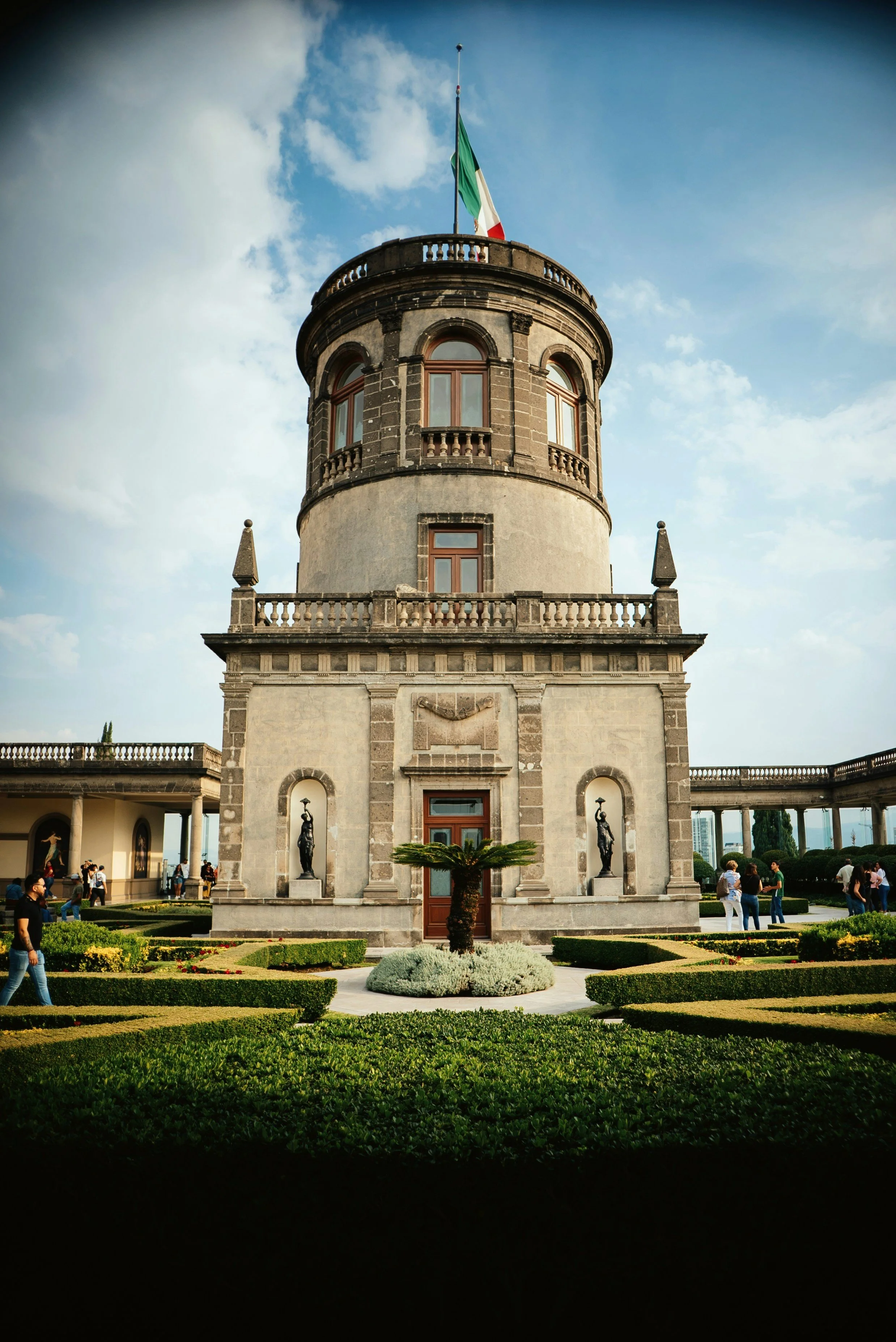 Domed stone tower with an arched entrance behind a lawn under a blue sky, Chapultepec, Mexico City.