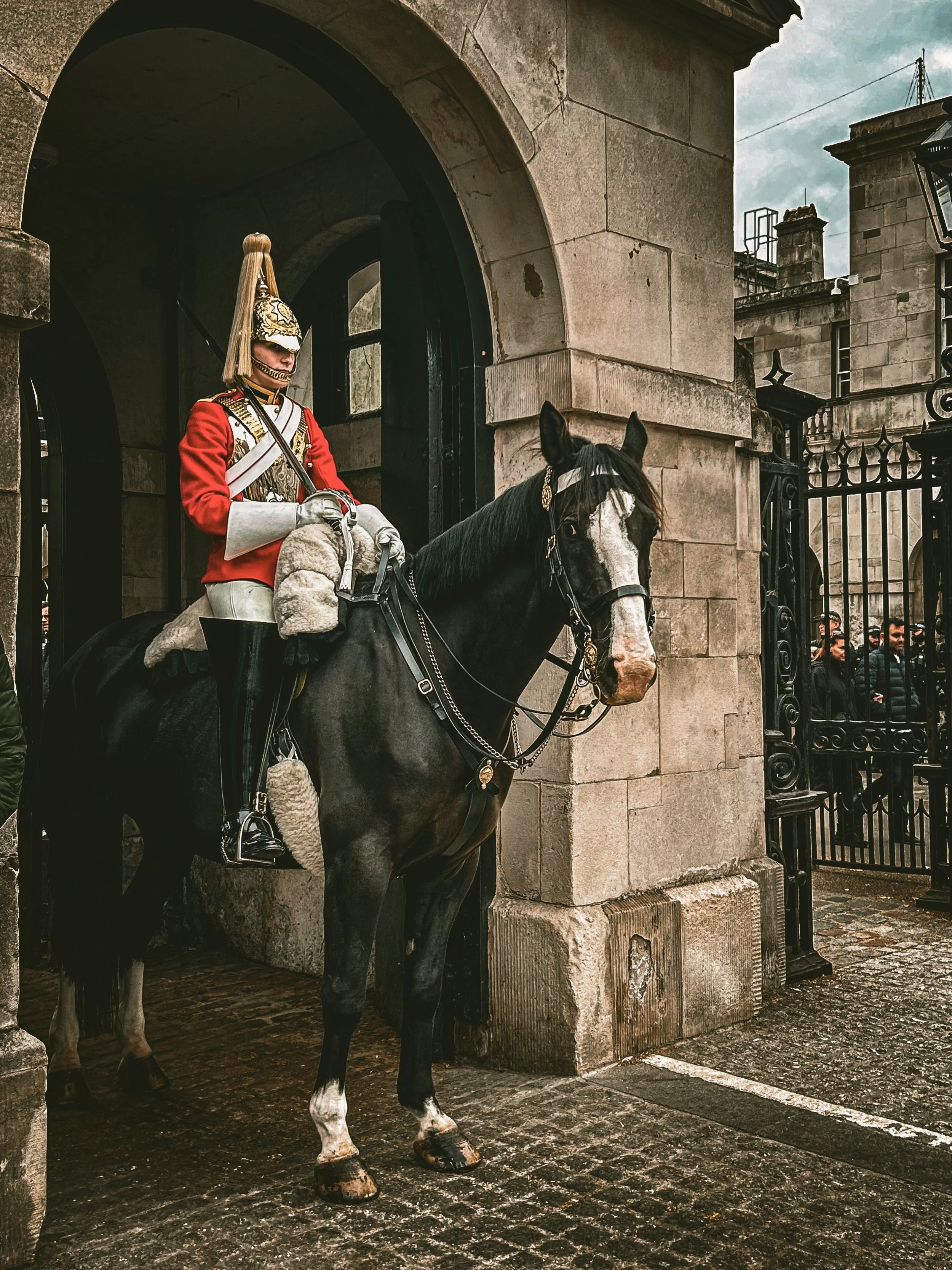 Mounted royal guard passing through a stone archway on horseback, London