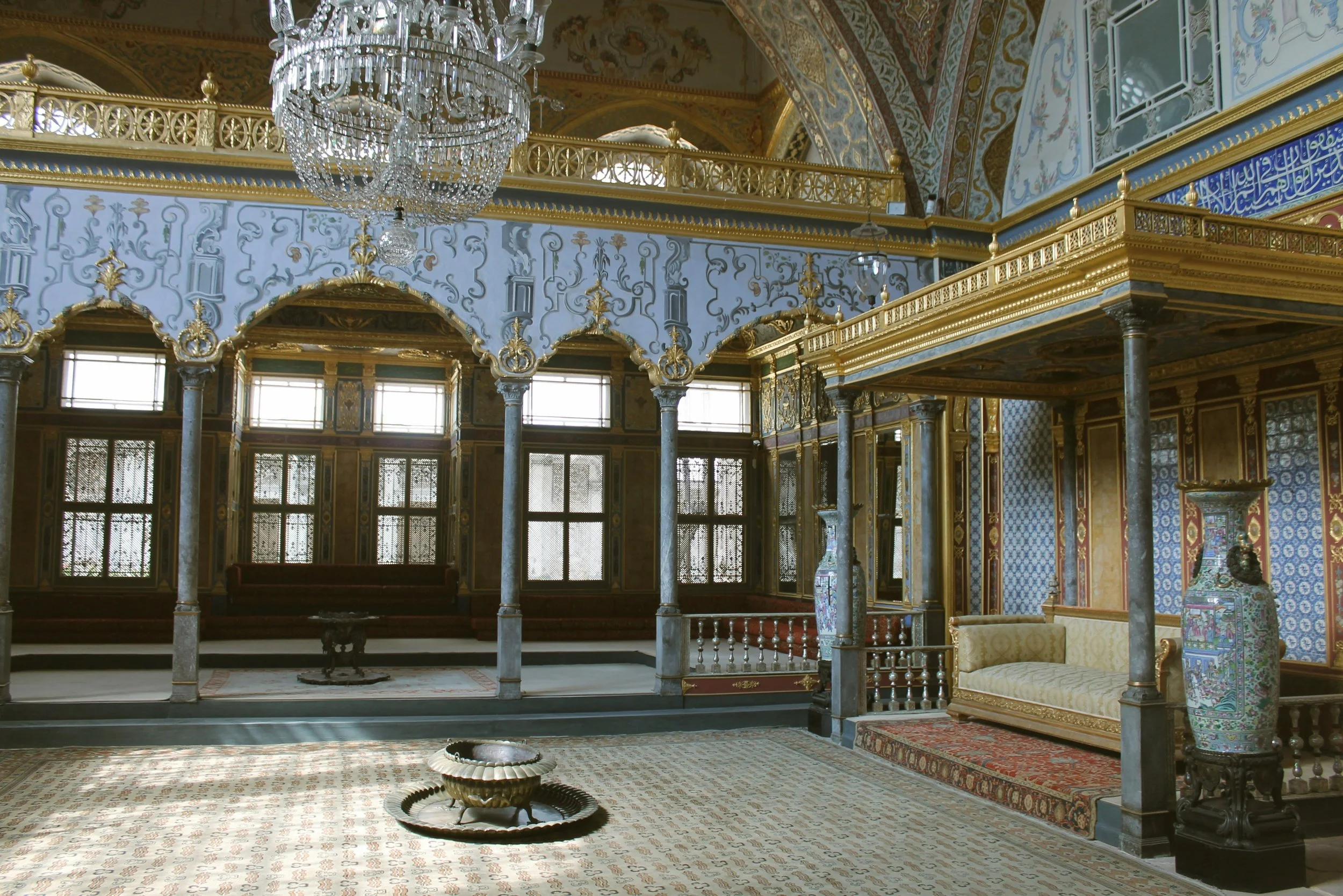 Ornate room with gold accents, a crystal chandelier, patterned walls and a raised platform with columns, Topkapı Palace, Istanbul