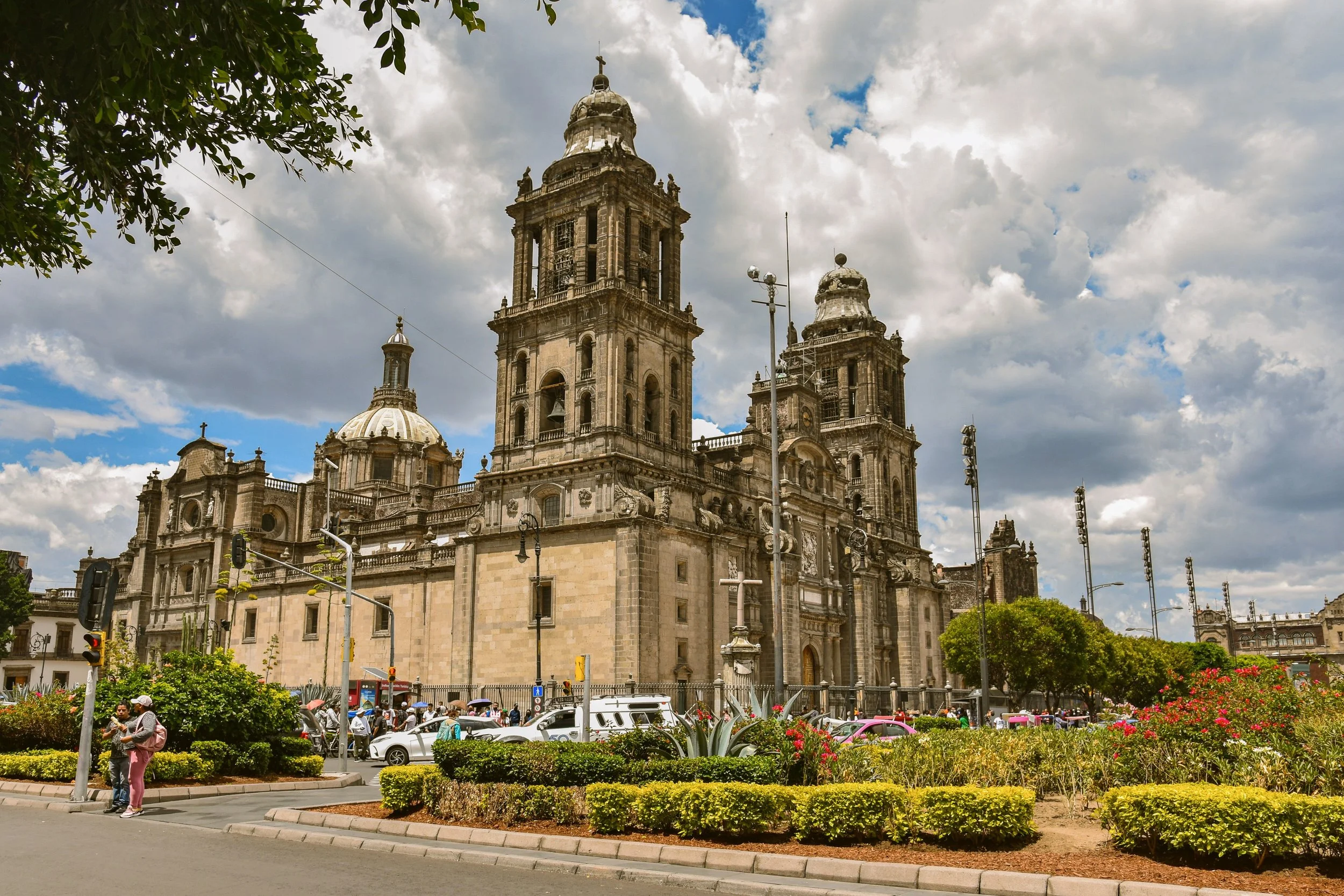 Metropolitan Cathedral with its twin bell towers and gardens in front under a cloudy sky, Mexico City.