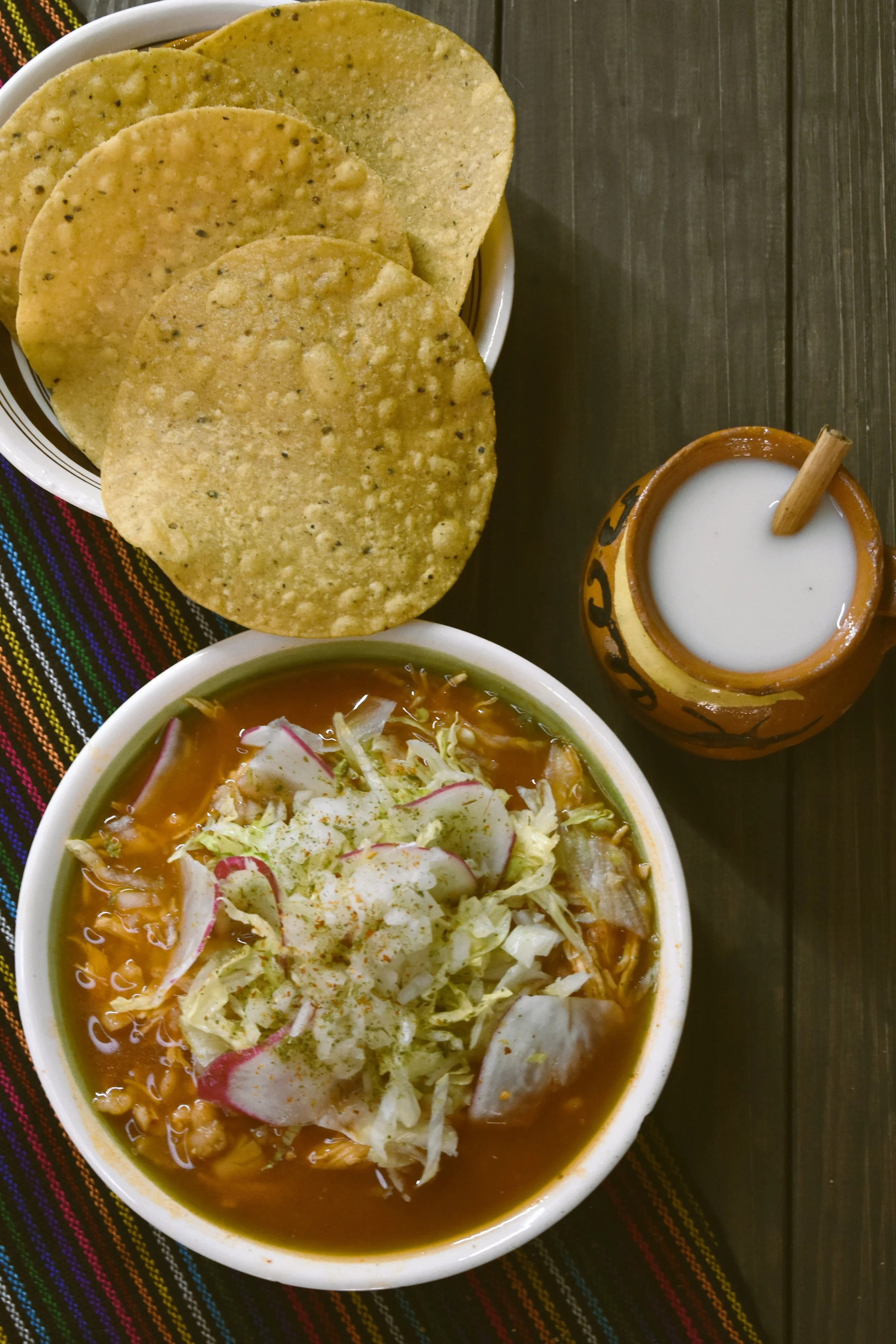 Bowl of pozole topped with lettuce and radish, served with tostadas and a drink, Mexico City.