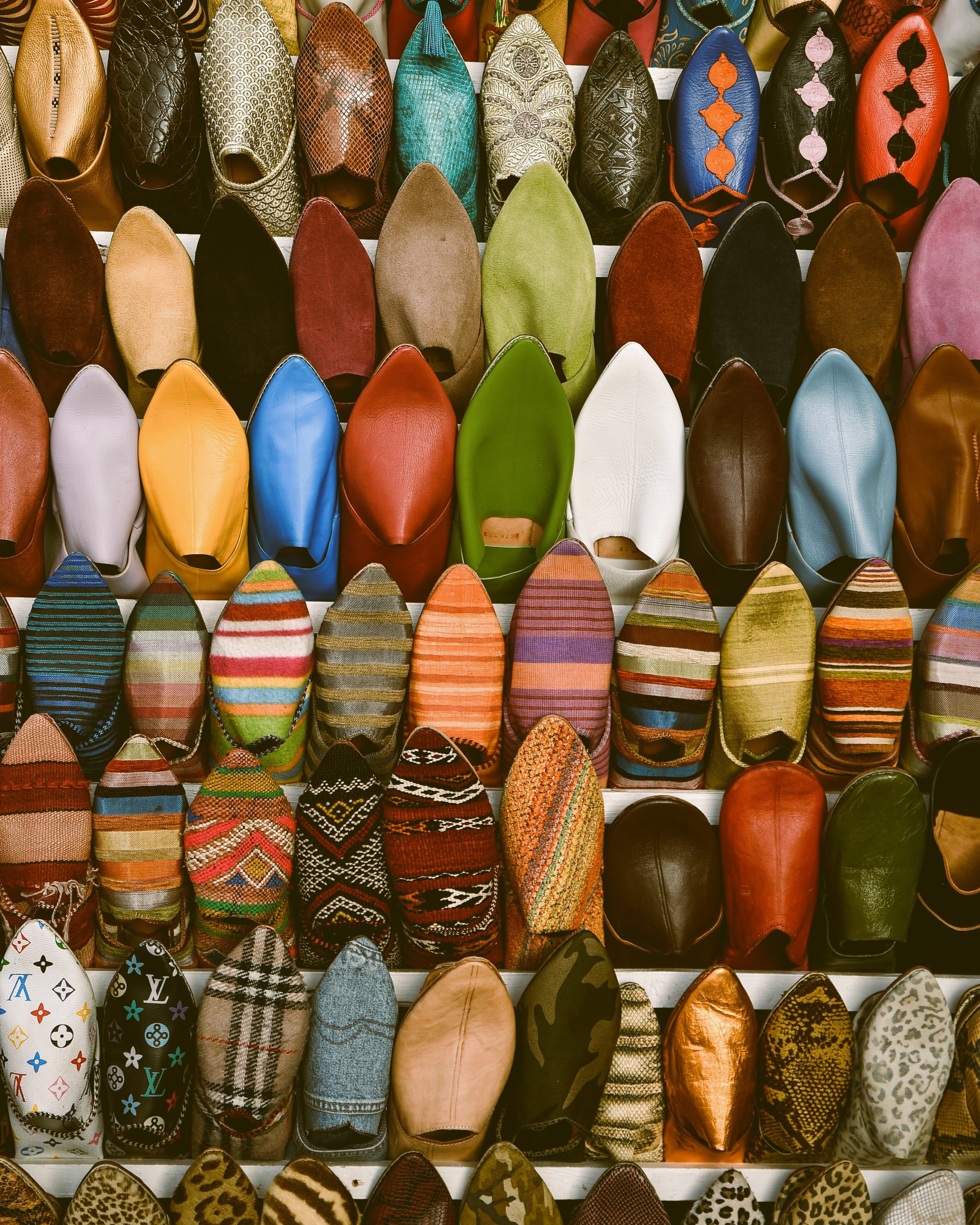 Wall of colorful leather babouche slippers hanging in rows at a souk stall, Marrakech.