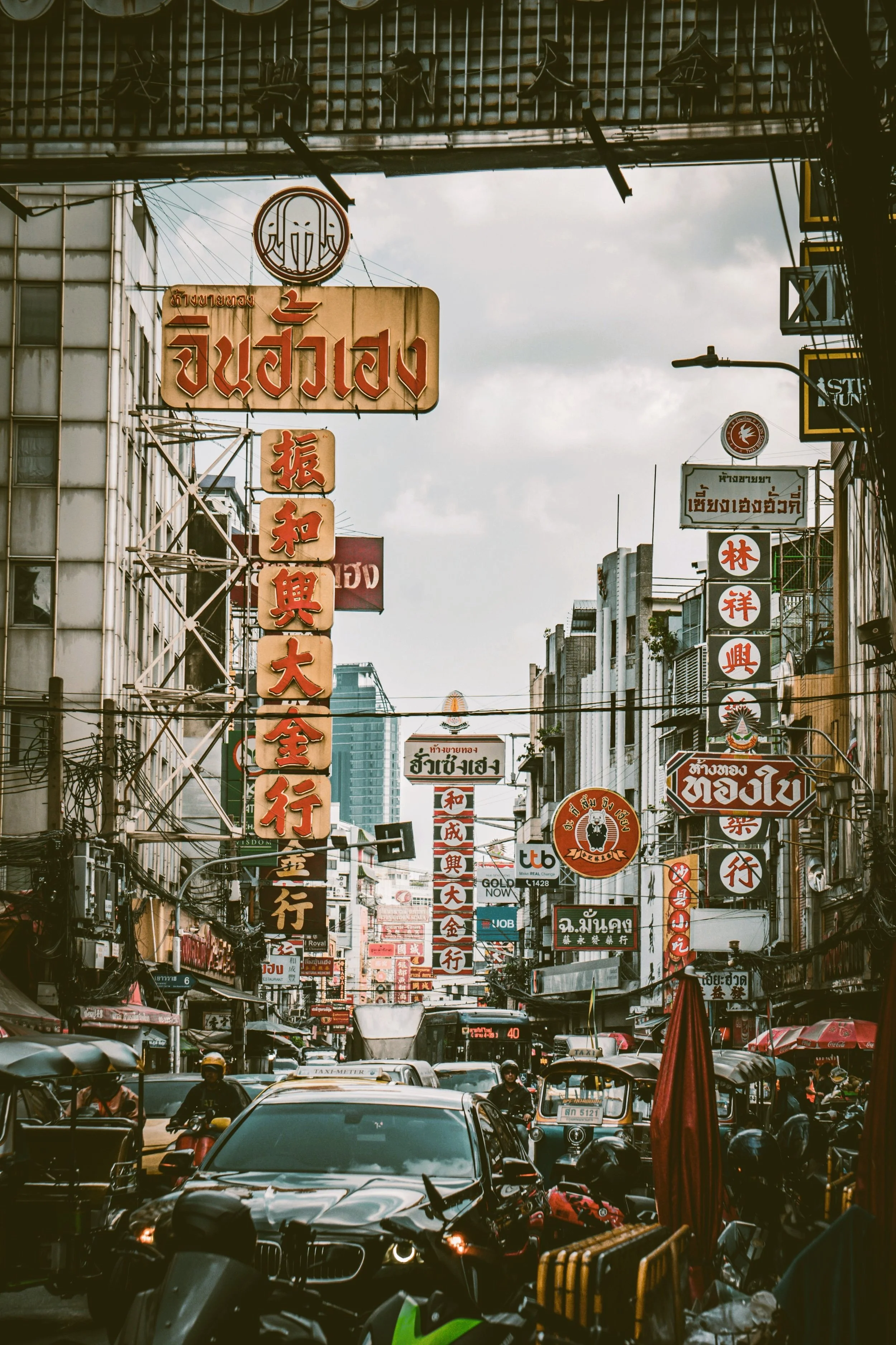 Street framed by an archway with vertical neon signs and traffic, Yaowarat, Chinatown, Bangkok.