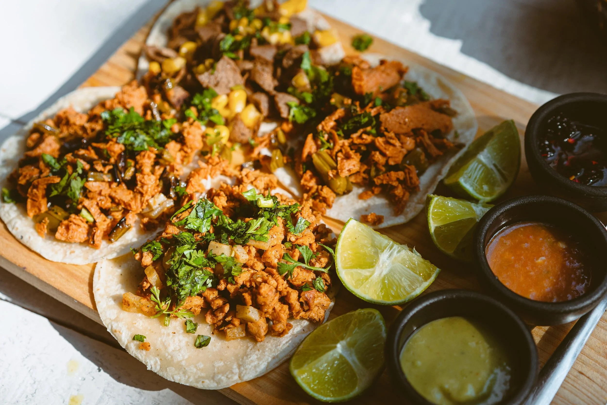 Plate of tacos topped with cilantro and onion, served with lime wedges and small bowls of salsa, Mexico City.