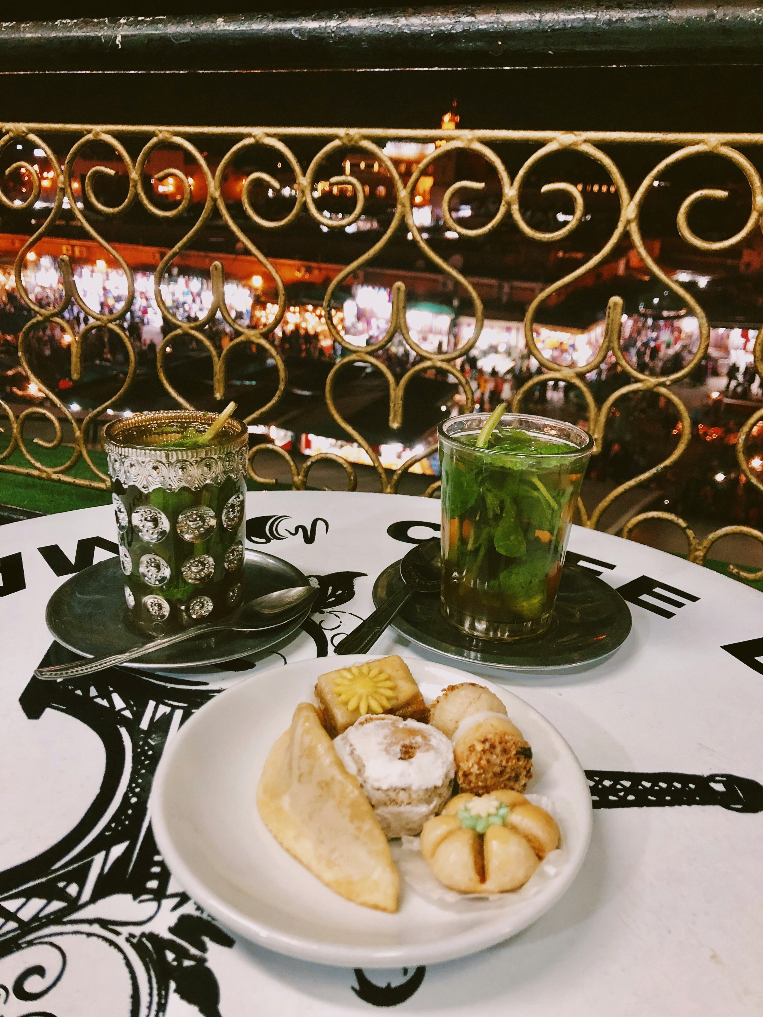 Plate of Moroccan dishes on a table beside a wrought-iron railing, Marrakech.