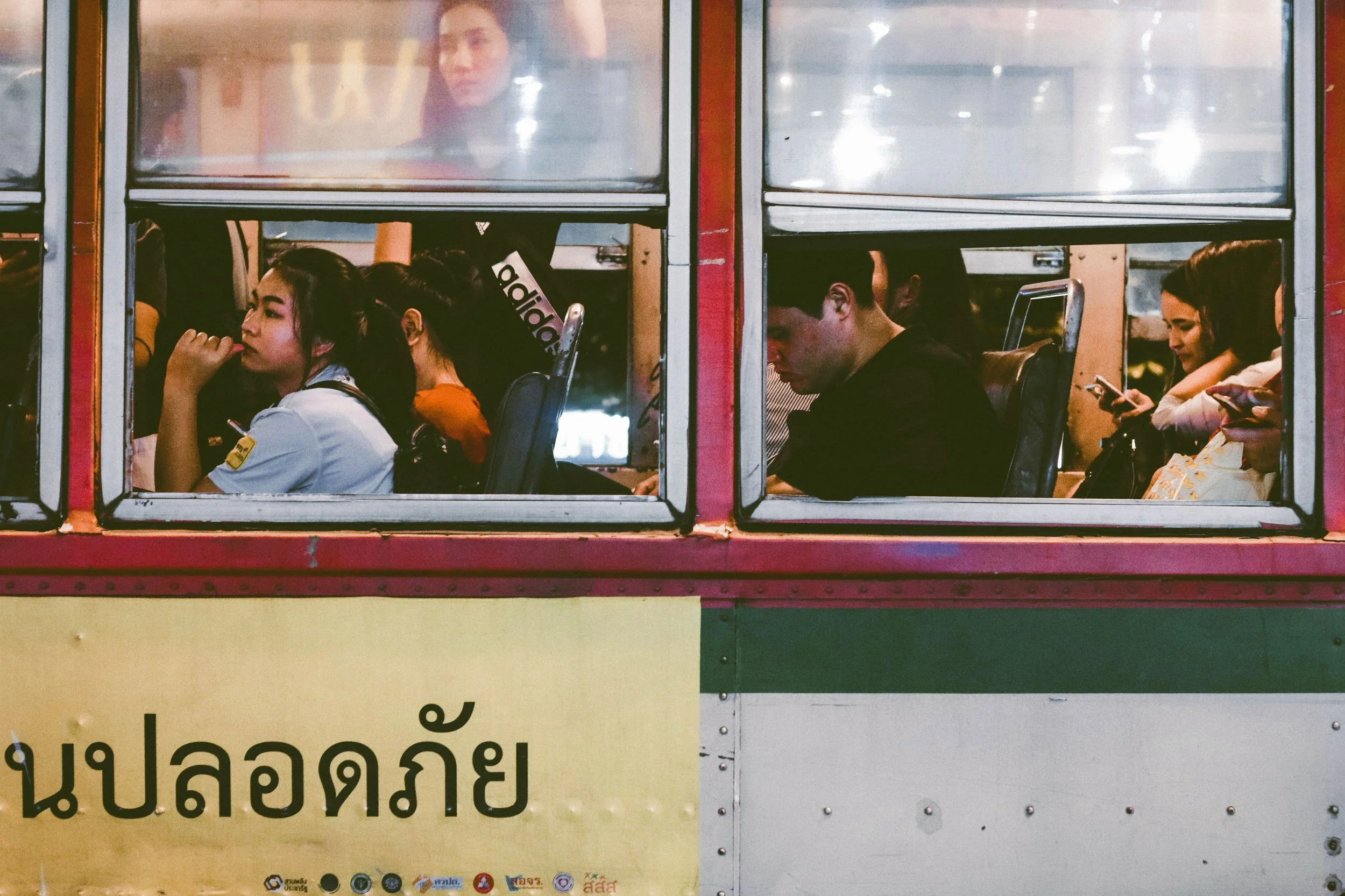 A bus seen through a window with people inside, Bangkok.