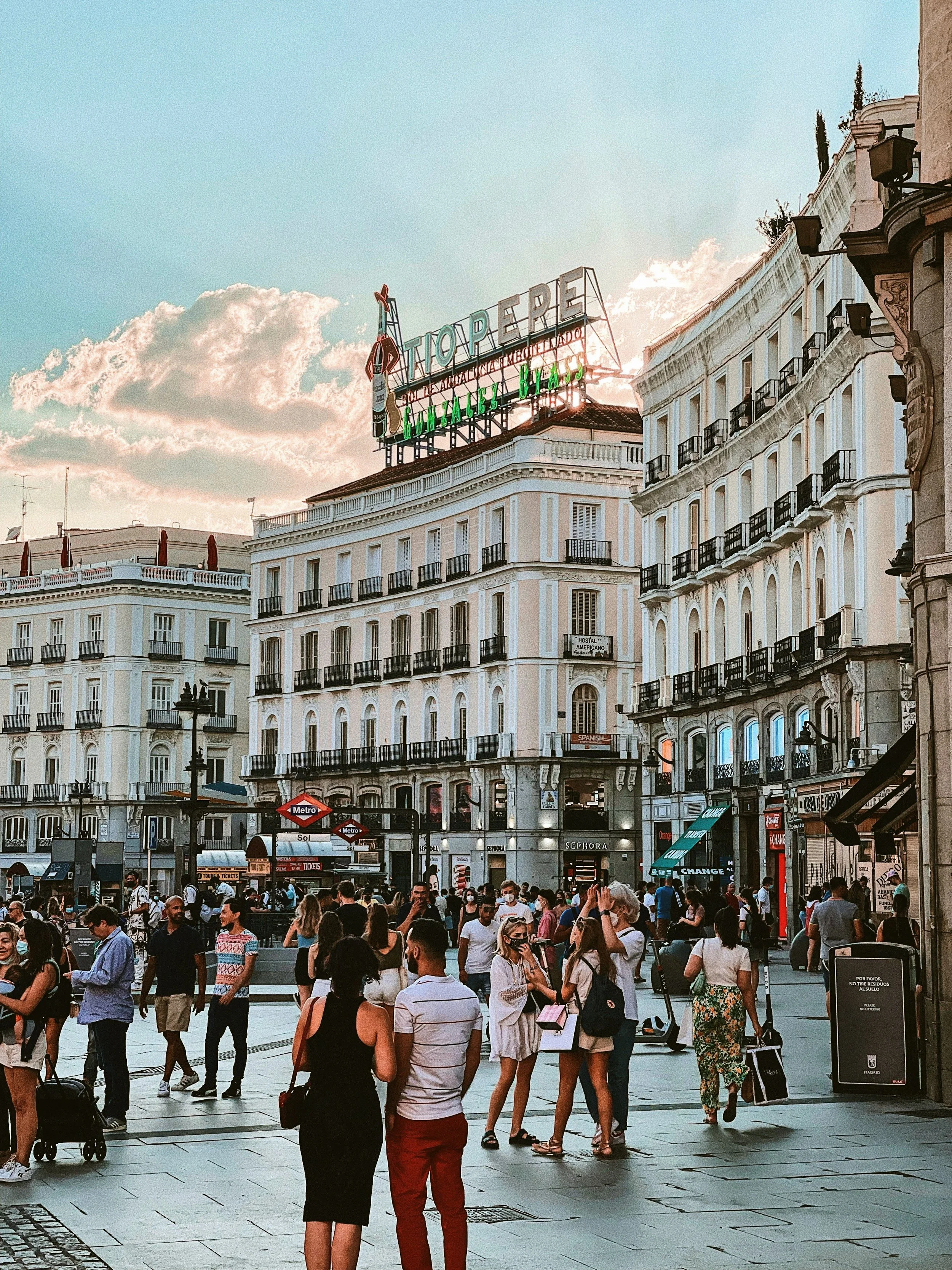 Crowded Puerta del Sol with the Tío Pepe sign above a cream building at sunset, Madrid
