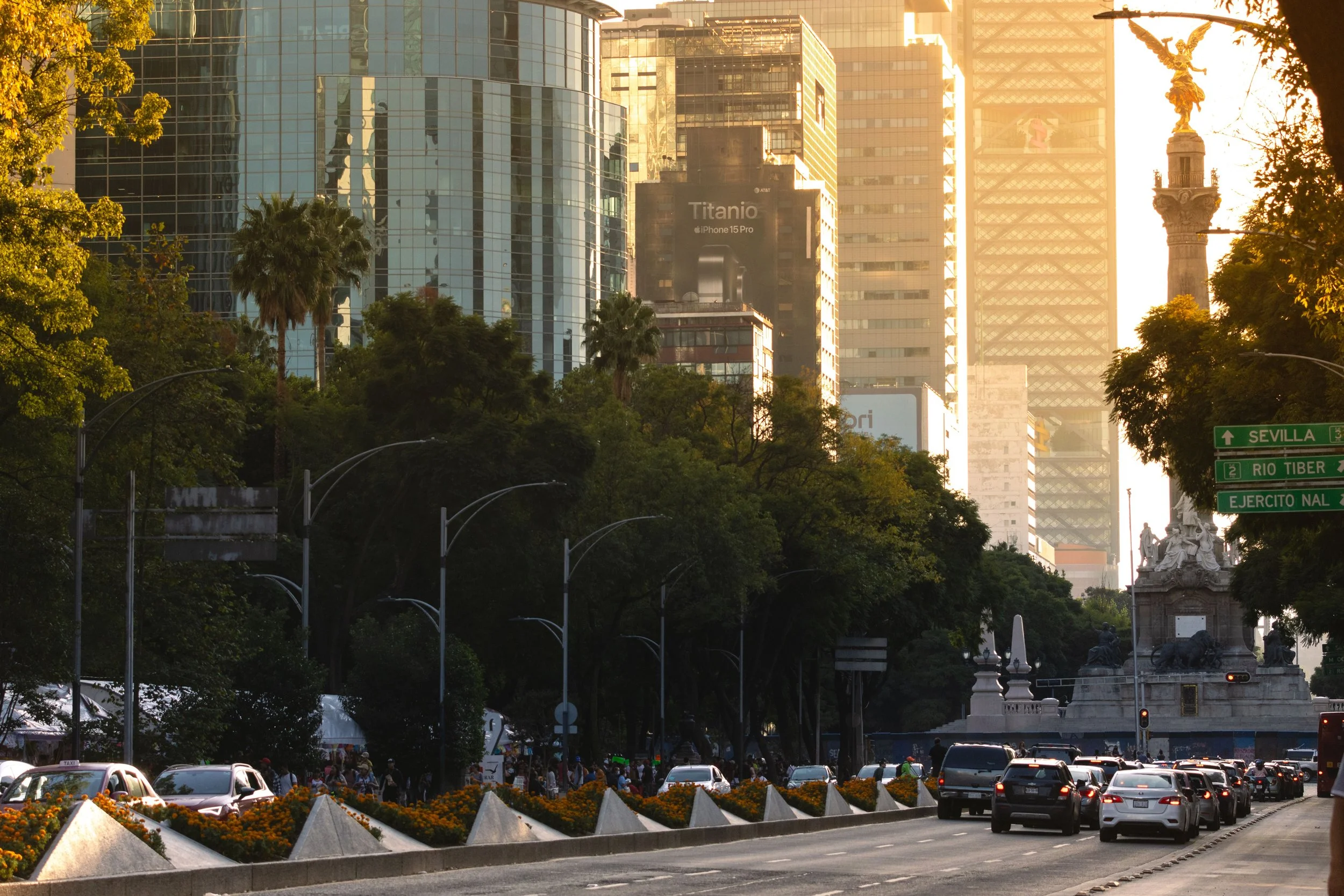 Paseo de la Reforma lined with trees and glass skyscrapers, with the Angel of Independence in the distance, Mexico City.