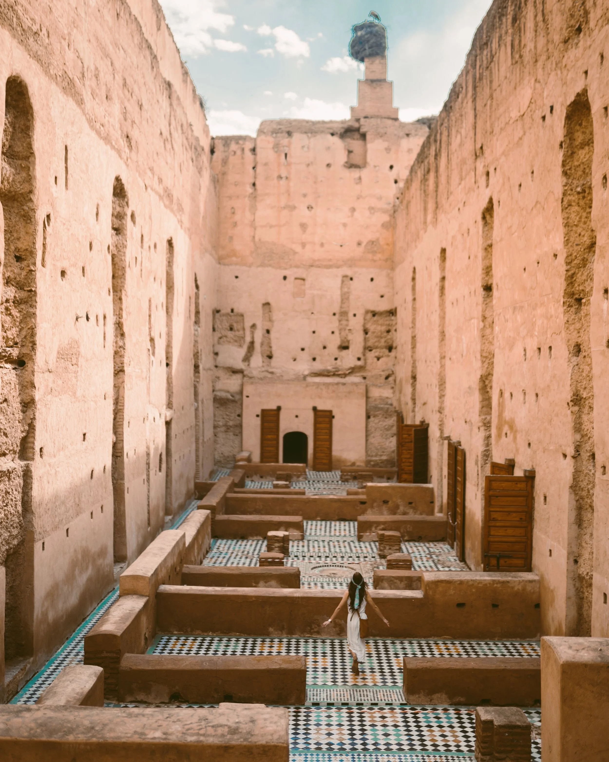 Empty passage between pink ochre walls of the ruined palace under a blue sky, El Badi Palace, Marrakech.