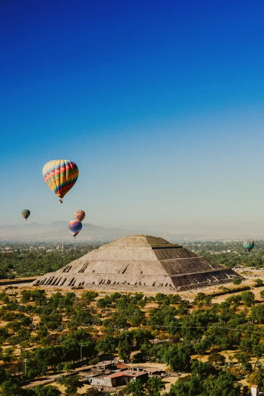 Hot air balloons floating over the Pyramid of the Sun at sunrise, Teotihuacán, Mexico.