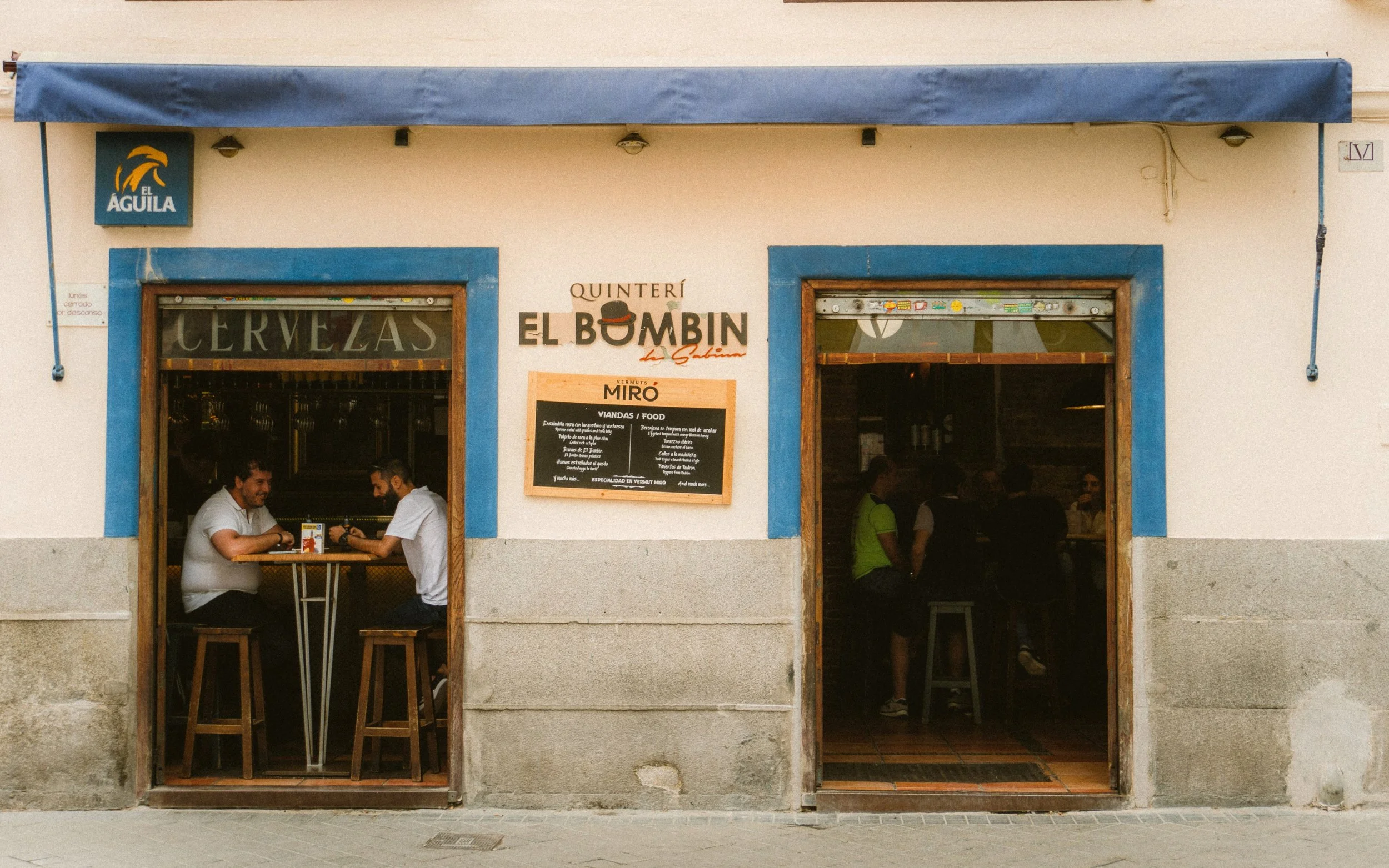 Locals having a drink inside a traditional Madrid bar with a blue-trimmed facade