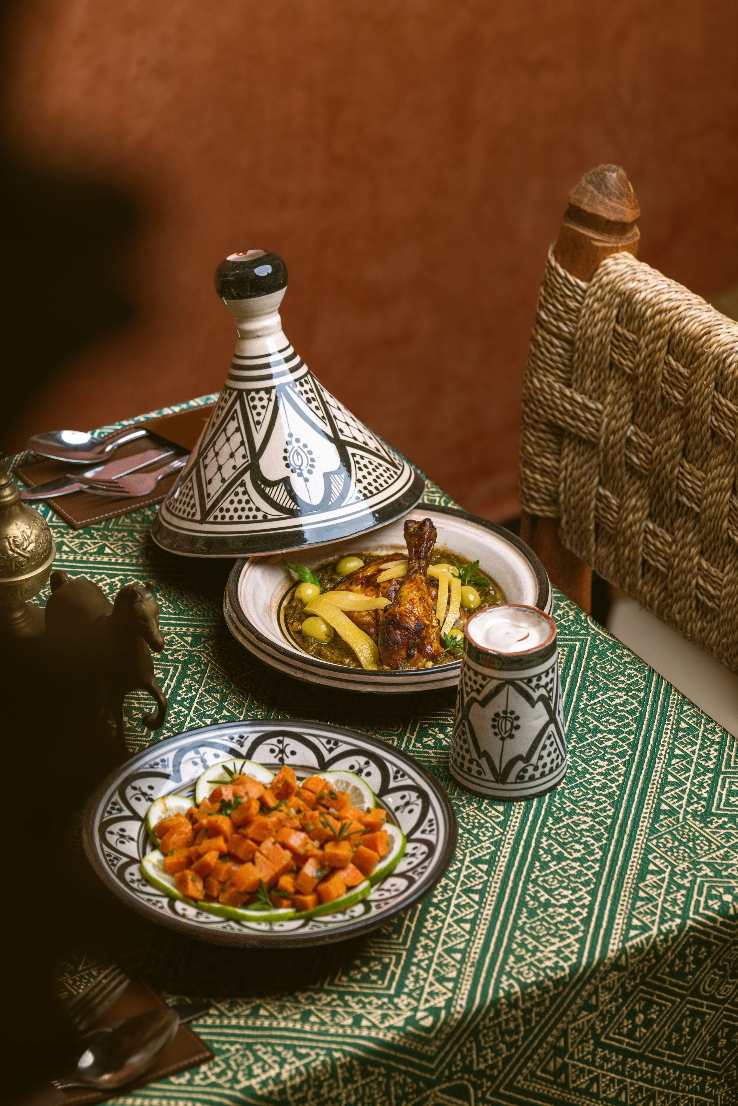 Tagine with a conical lid and a dish of food on a decorated table, Marrakech.