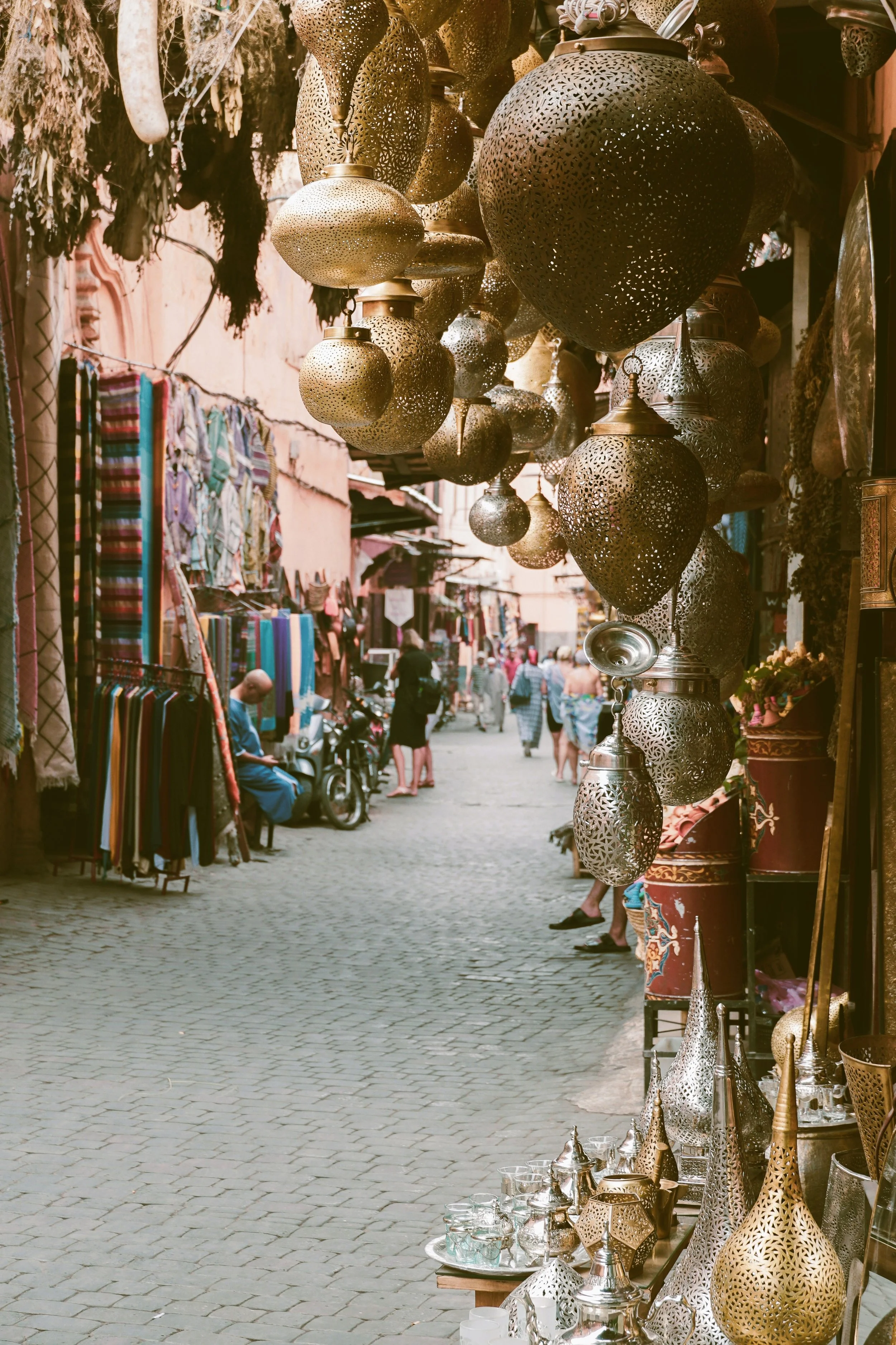Narrow souk street with baskets and lamps hanging overhead, Marrakech.